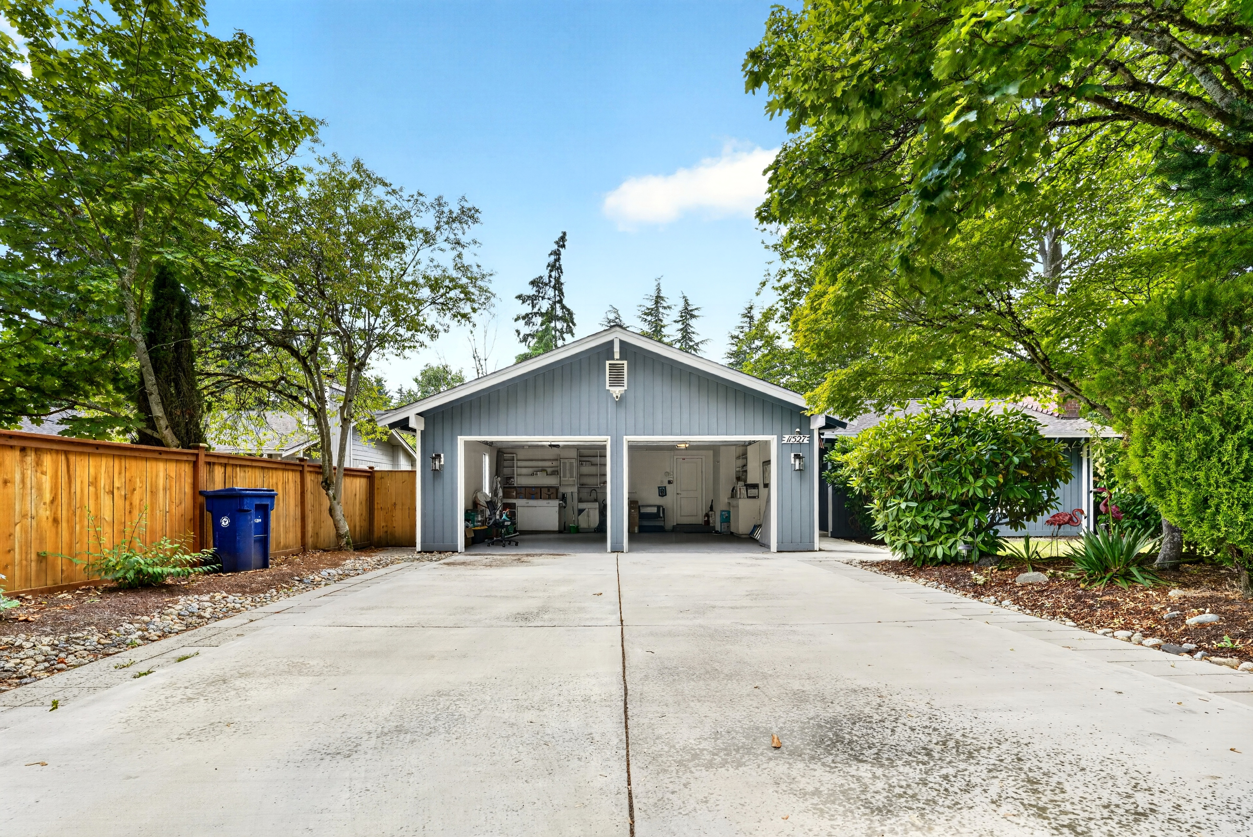 Spacious driveway and 2-car garage framed by lush, mature trees