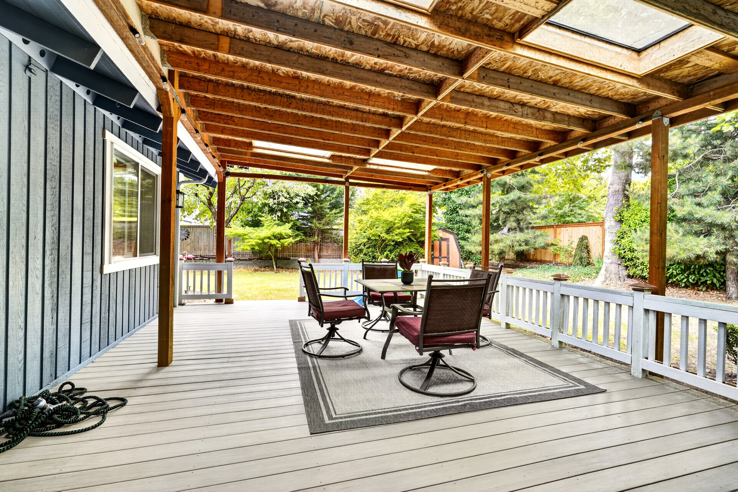 Spacious covered deck with outdoor dining and peaceful backyard views