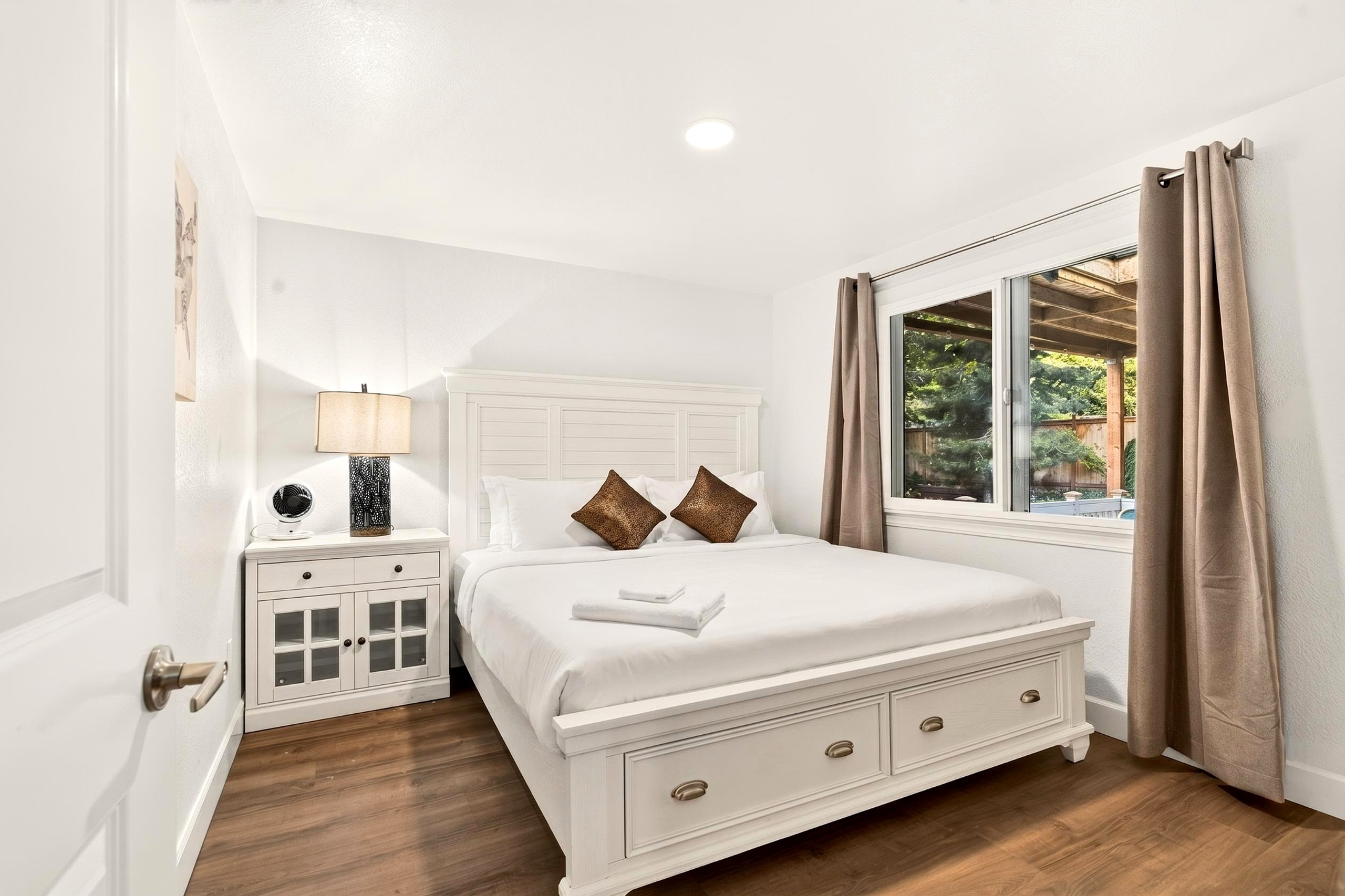 Bright, cozy bedroom with natural light, storage bed, and garden views