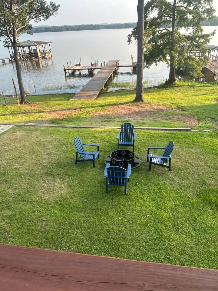 Fire pit with Adirondack chairs on the lawn above the dock