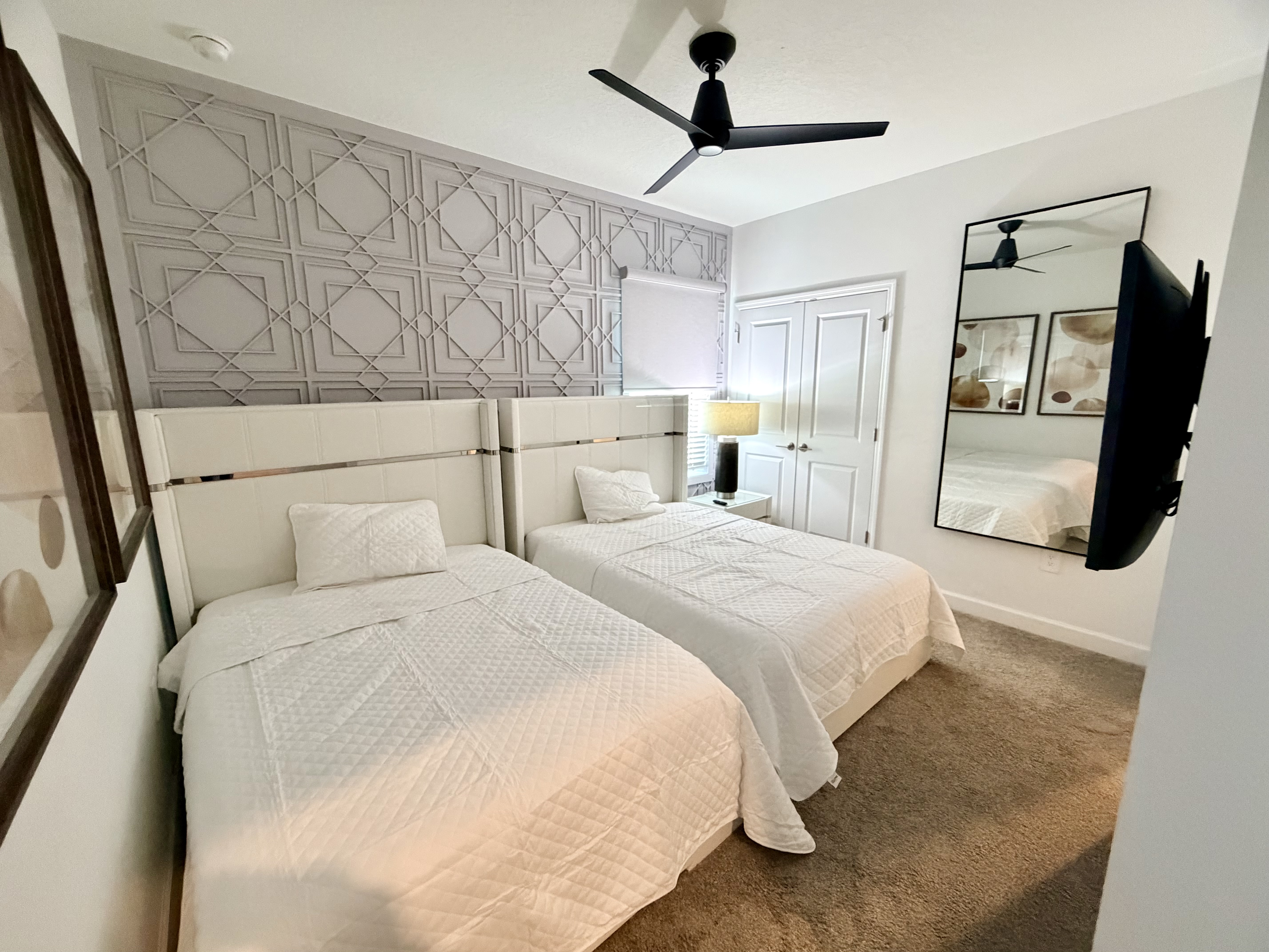 Bright double-queen bedroom with stylish accent wall and mounted TV