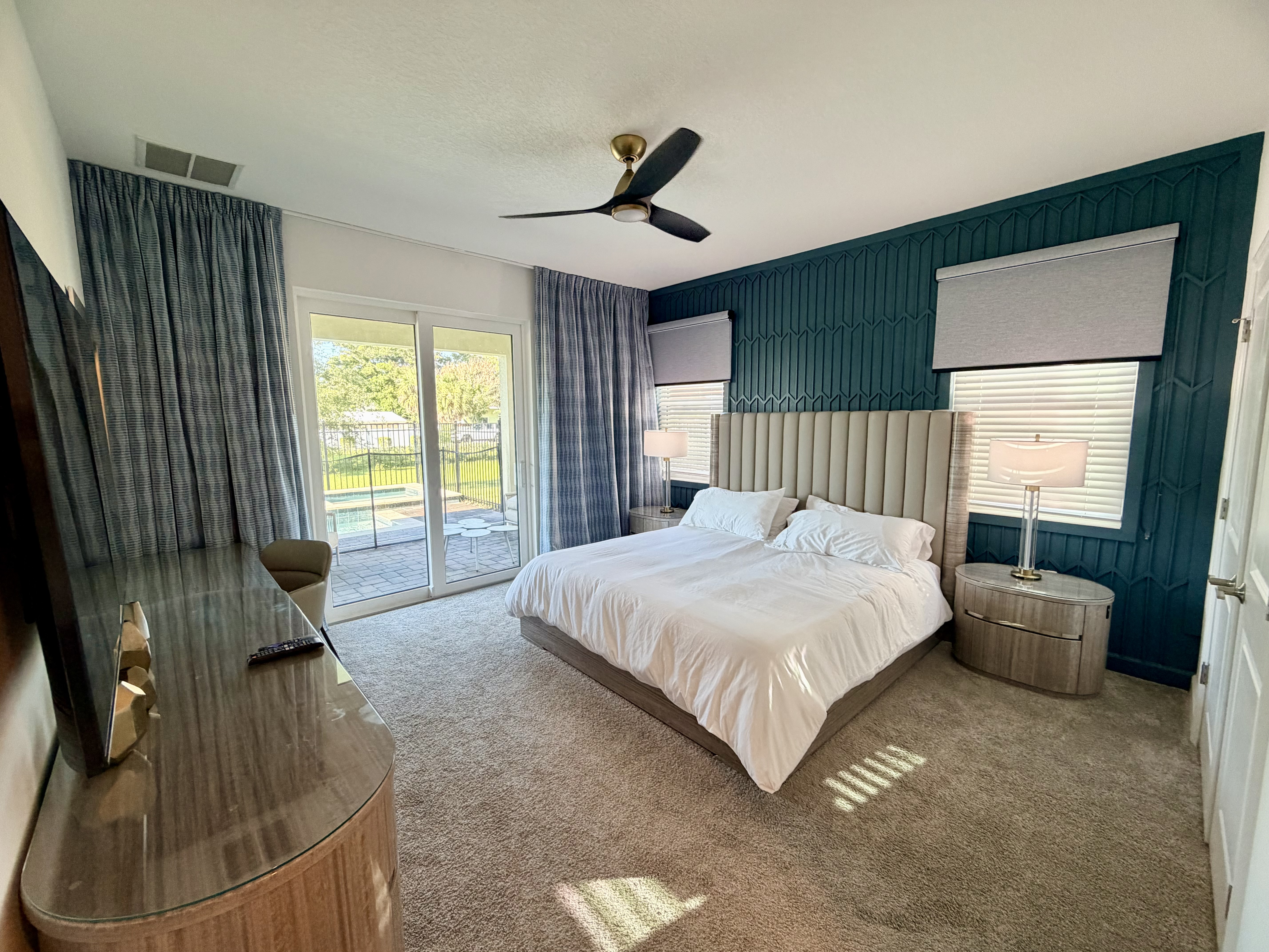 Bright king bedroom with patio access and stylish teal accent wall