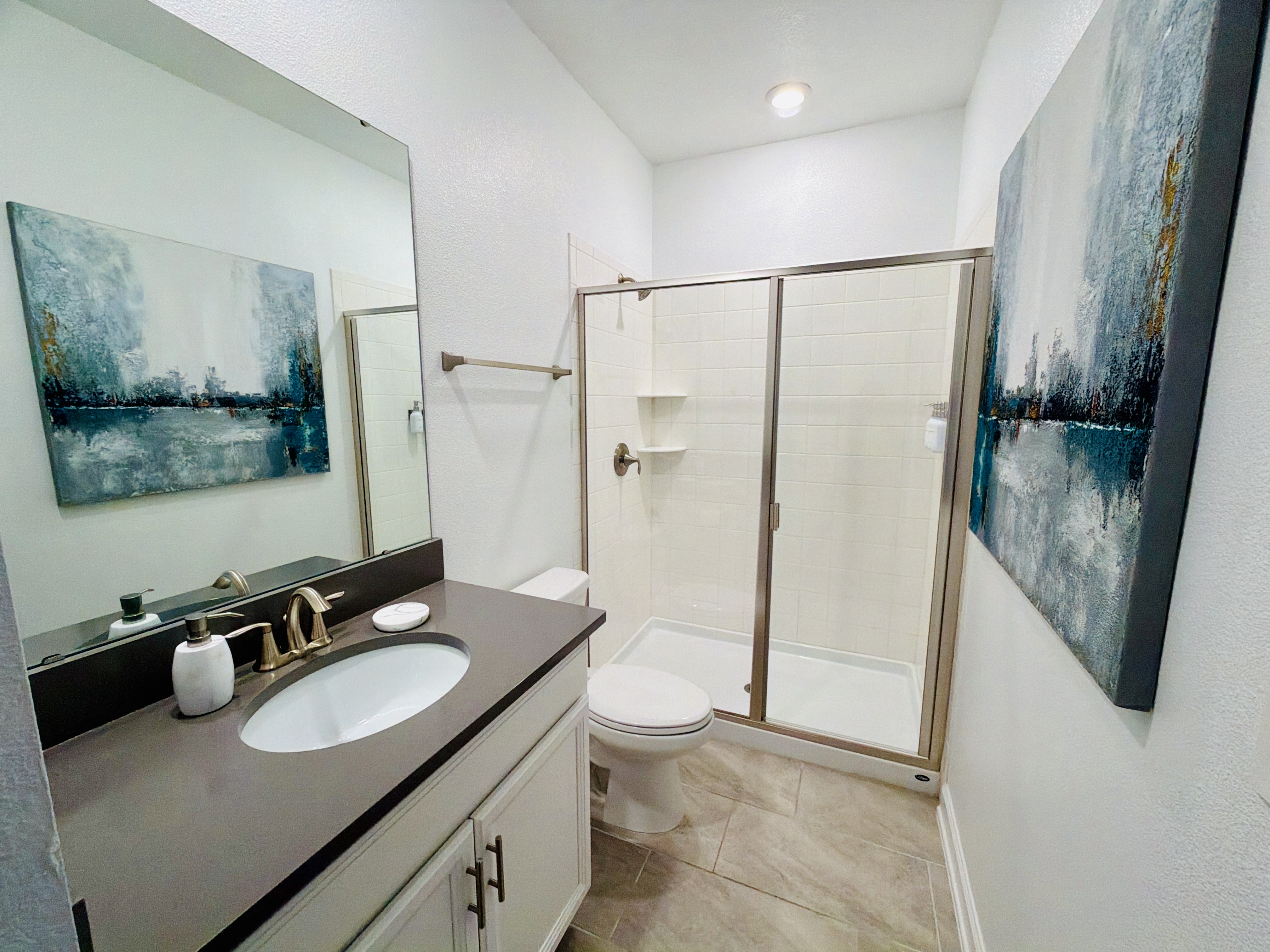 Bright modern bathroom with glass walk-in shower and sleek vanity