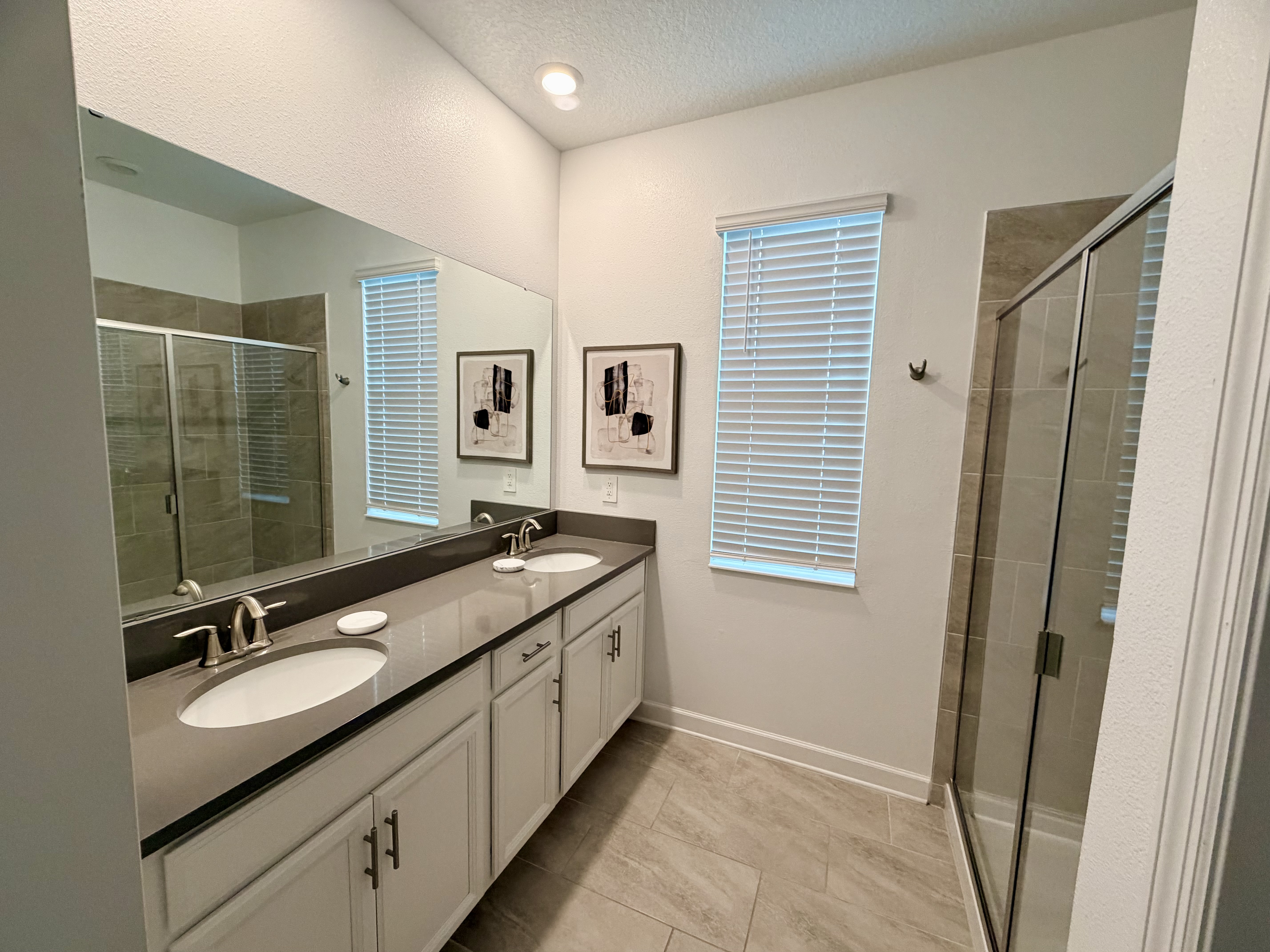 Bright bathroom with double vanity and sleek glass walk-in shower