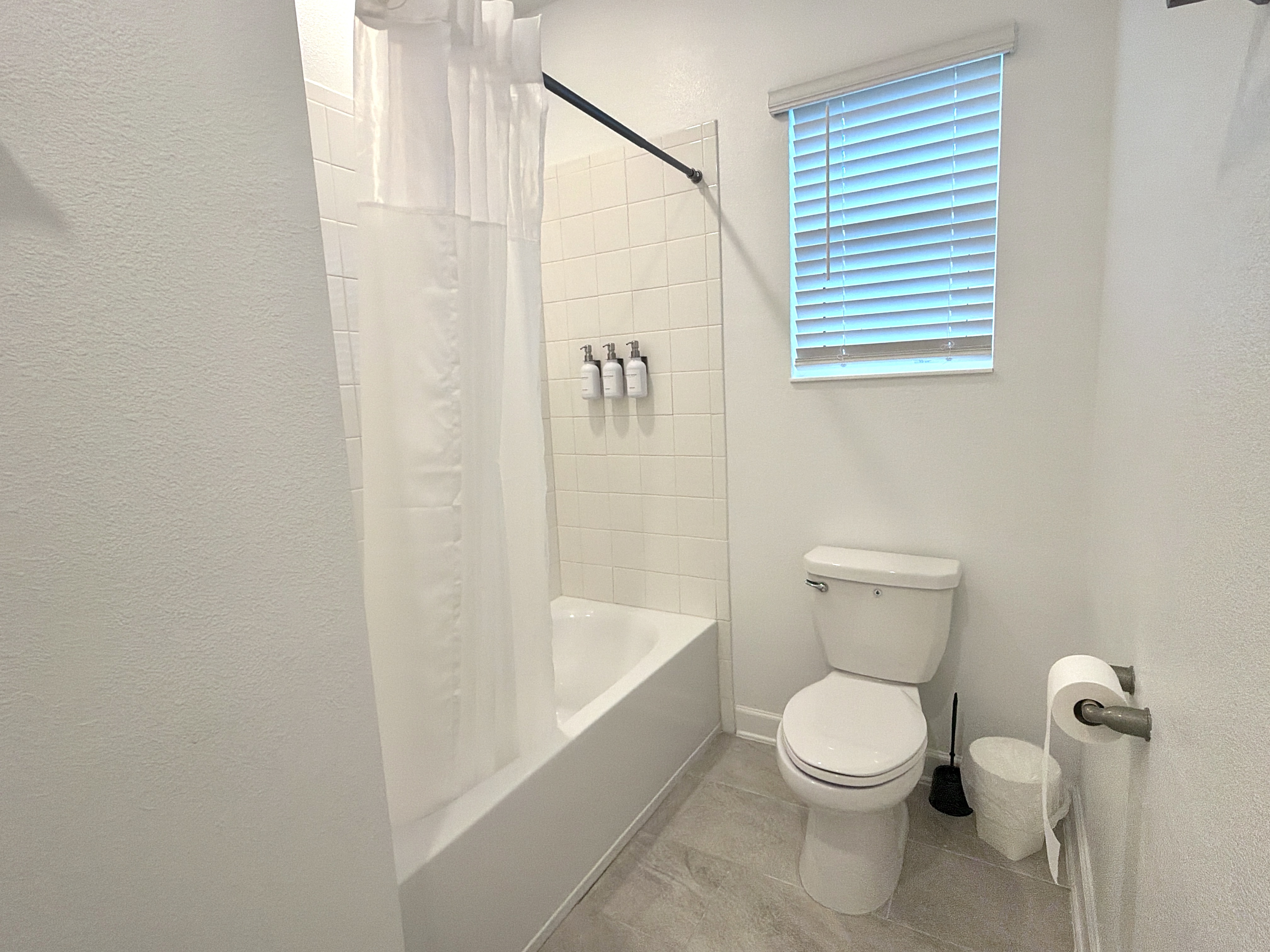 Bright full bathroom with tub-shower combo and fresh, modern finishes