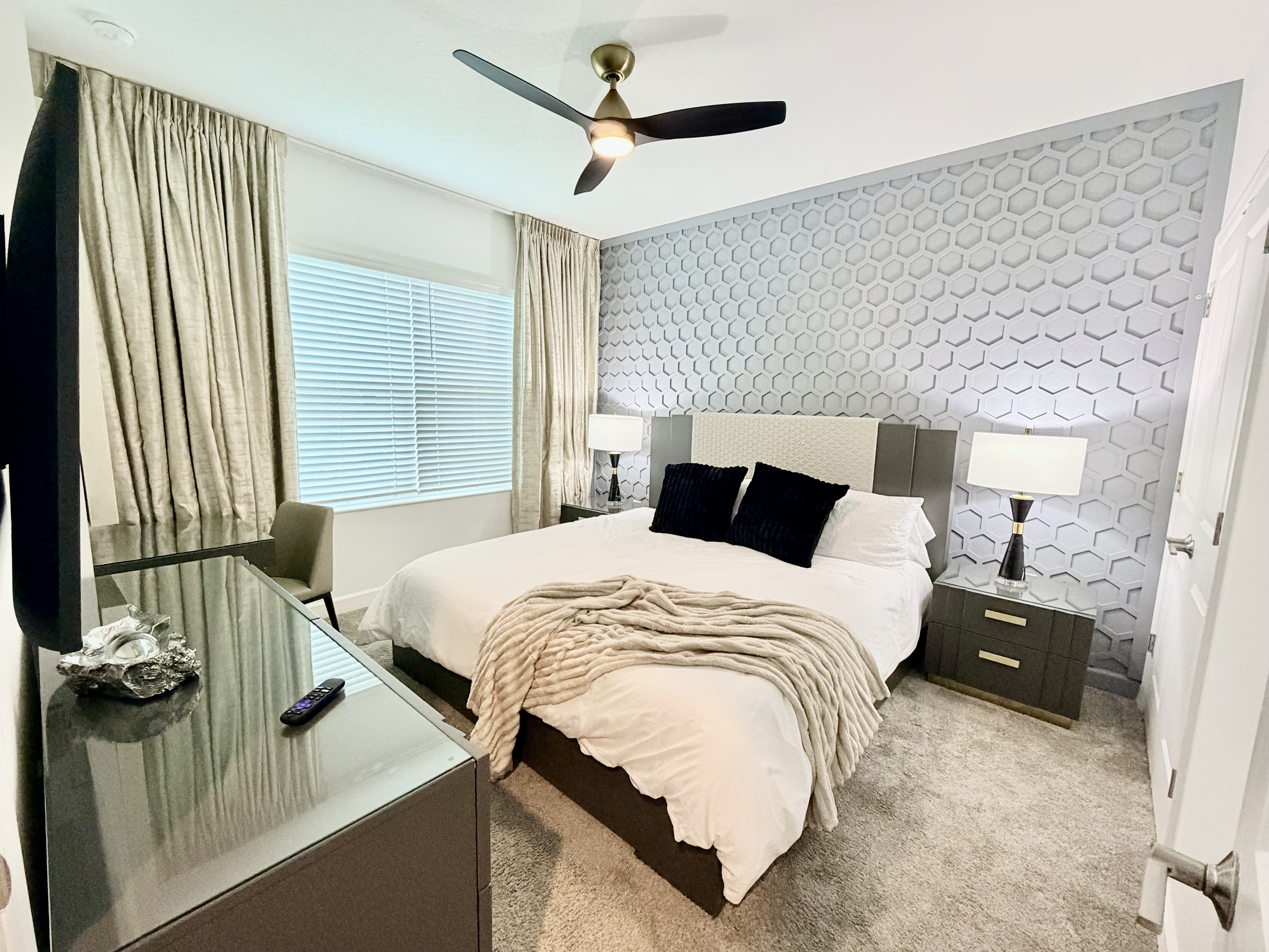 Modern king bedroom with designer accent wall, TV, and cozy finishes