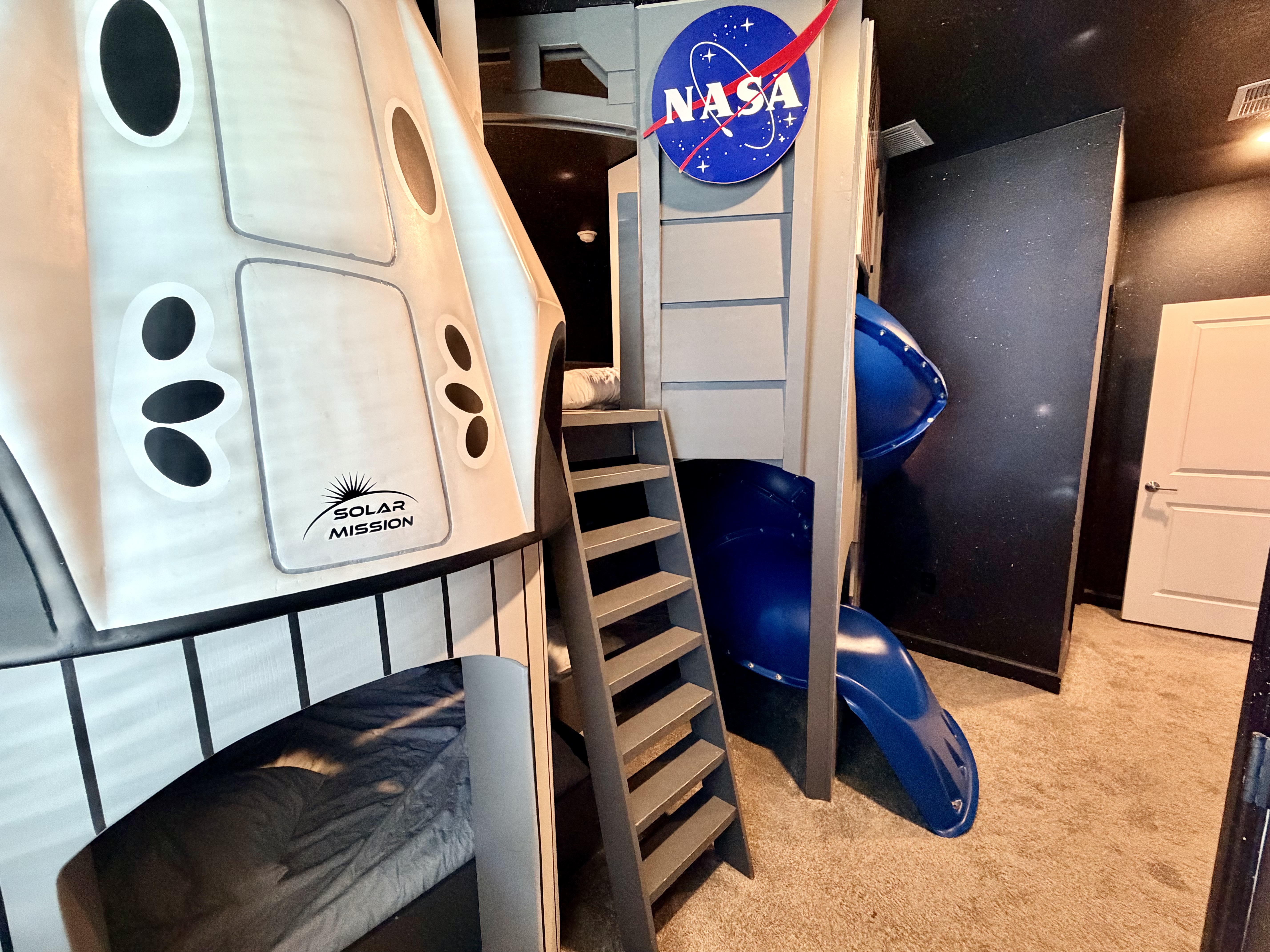 Epic NASA-themed bunk room with space shuttle bed and slide