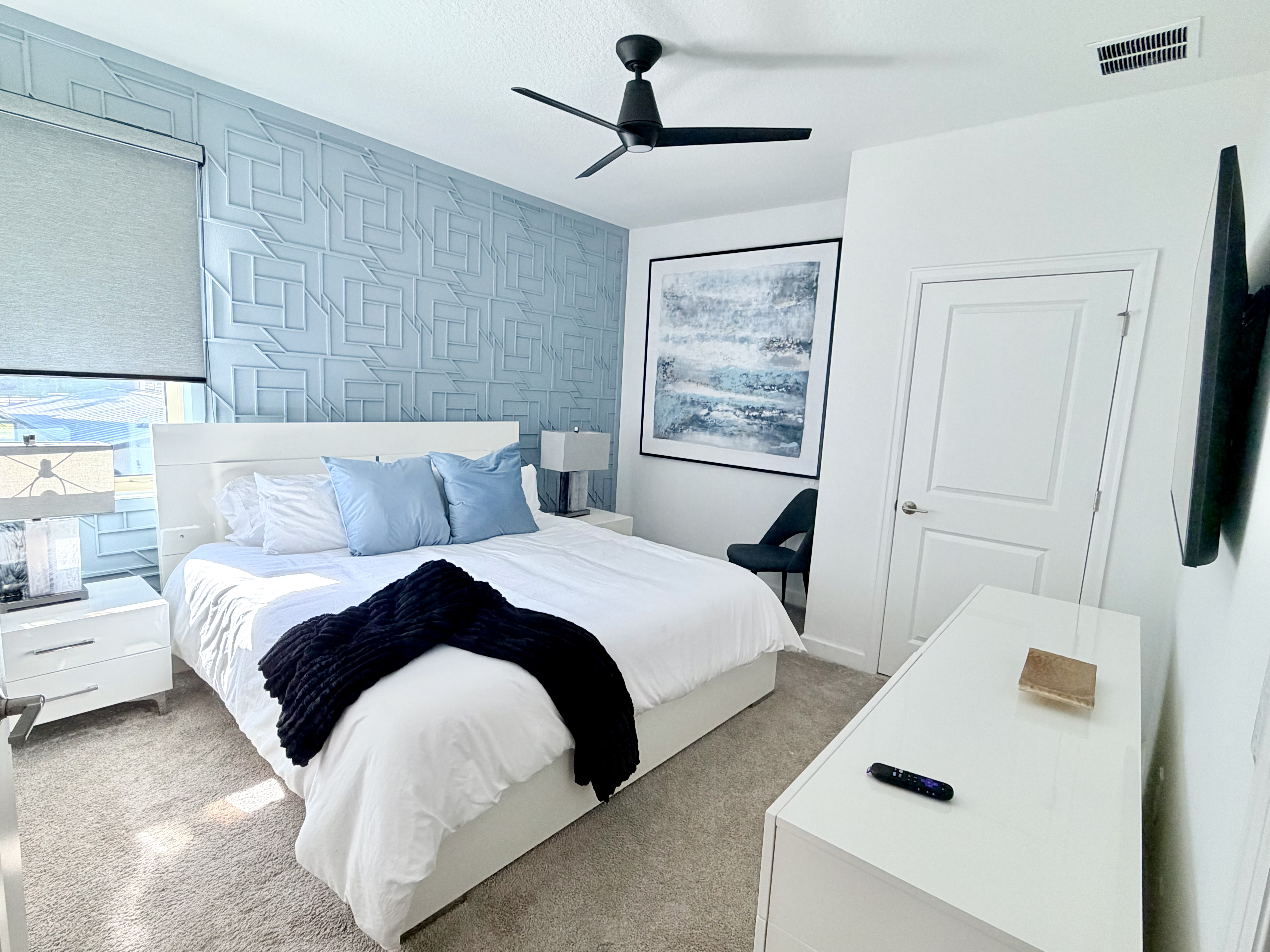 Bright modern bedroom with designer accent wall, TV, and natural light