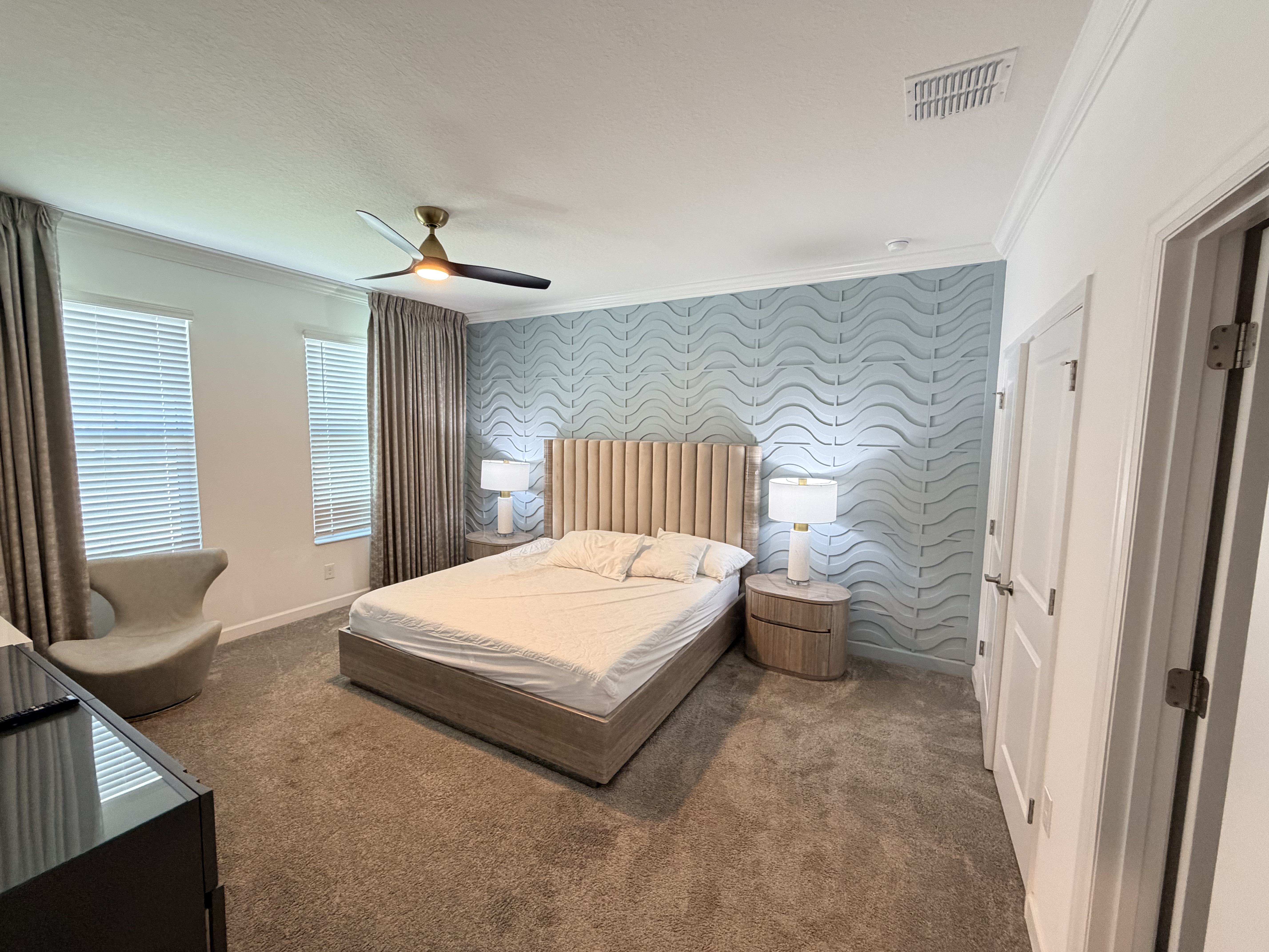 Spacious king bedroom with designer accent wall and soft natural light