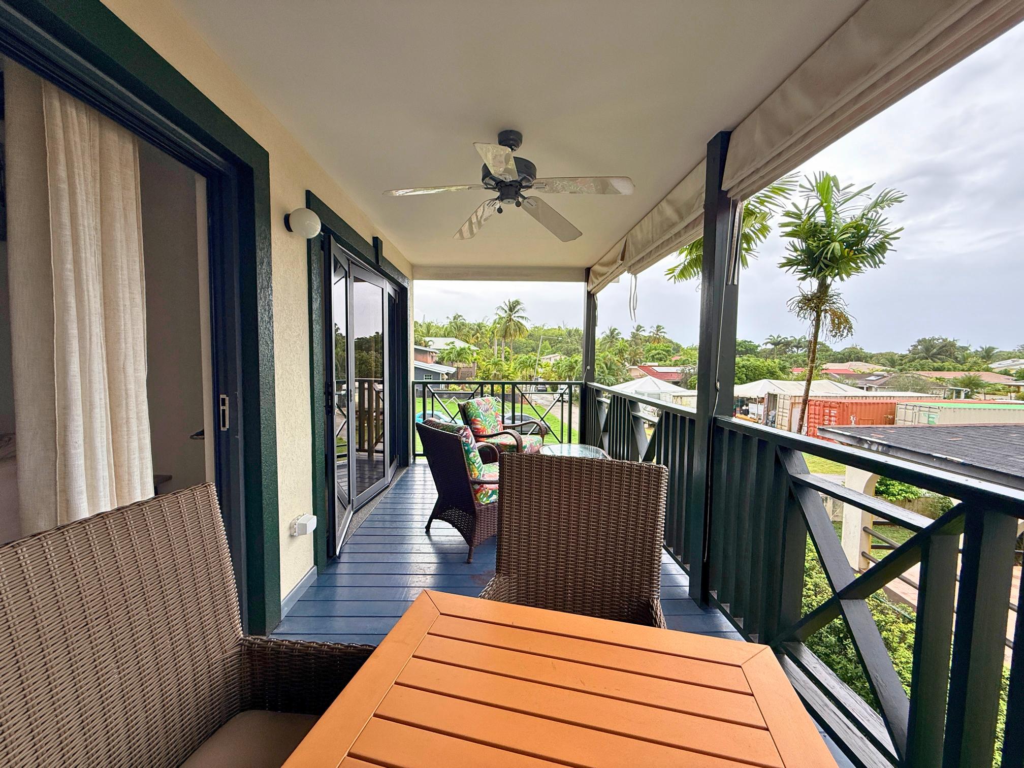 Covered tropical balcony with dining seating and relaxing neighborhood views