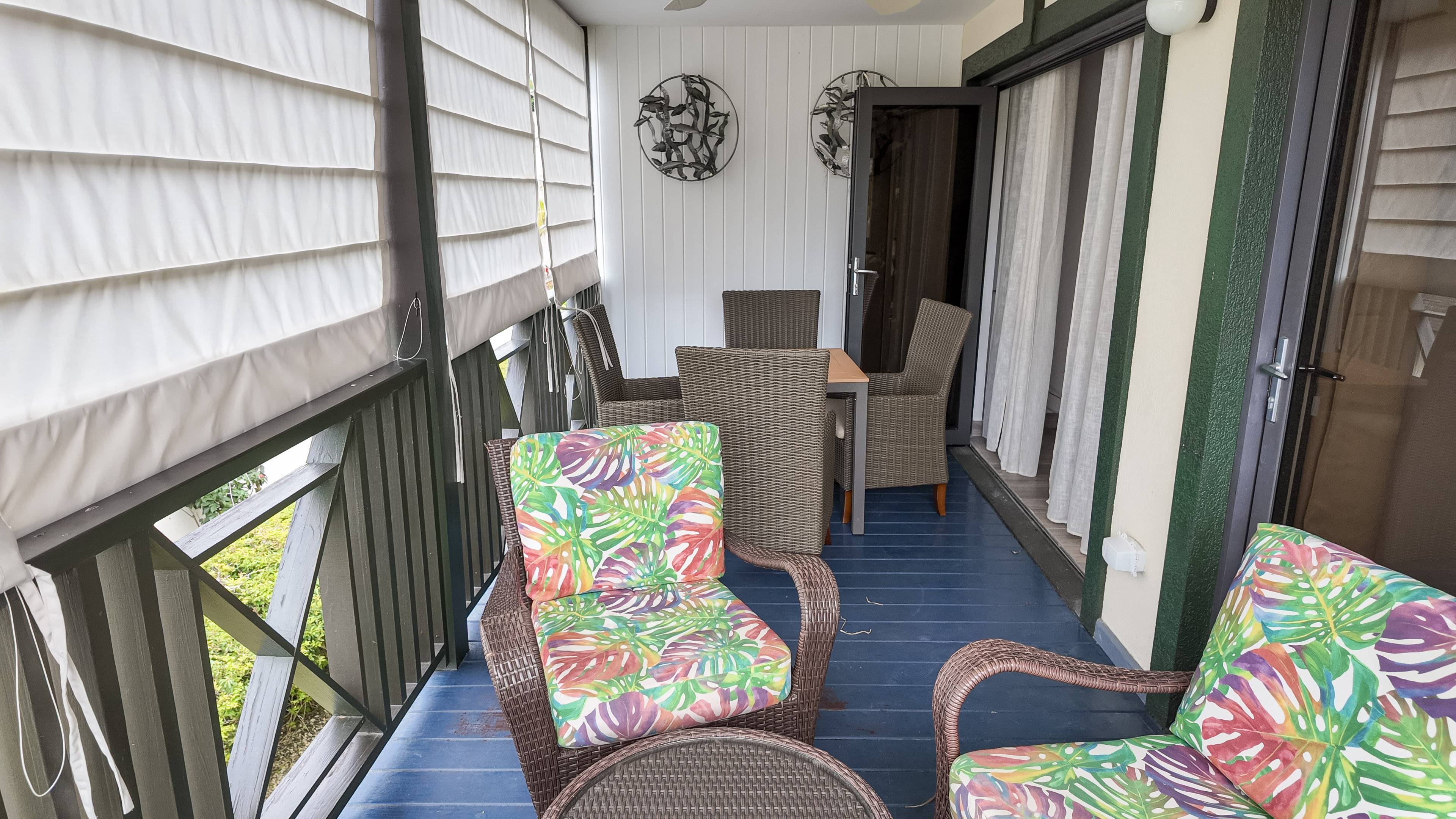 Covered tropical balcony with wicker seating and private outdoor dining