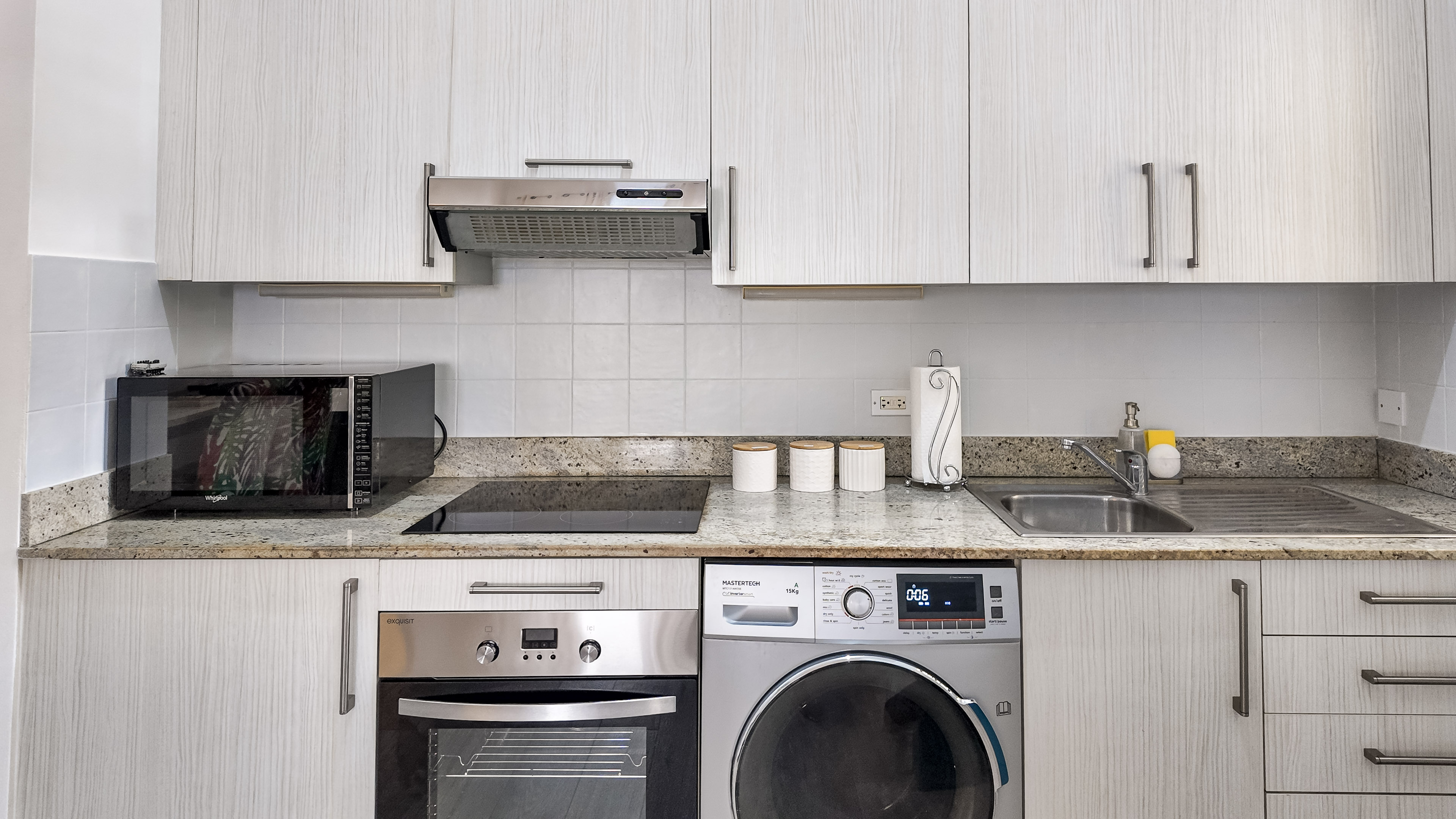 Modern kitchen with washer, oven, microwave, and bright clean finishes