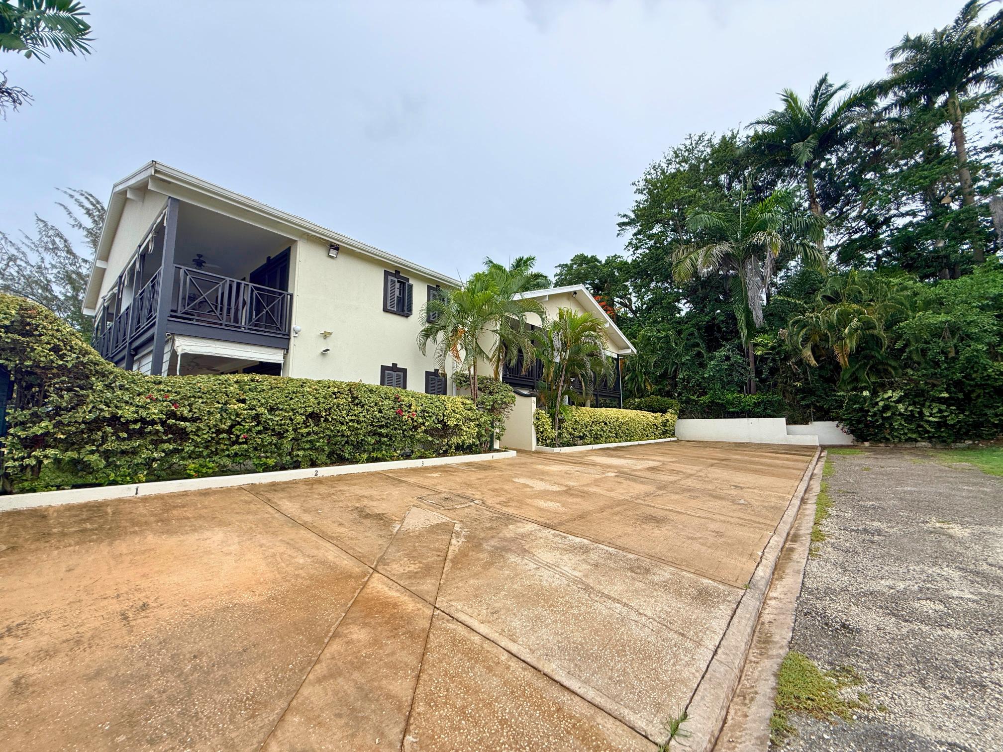 Tropical villa with large driveway, balconies, and lush private grounds