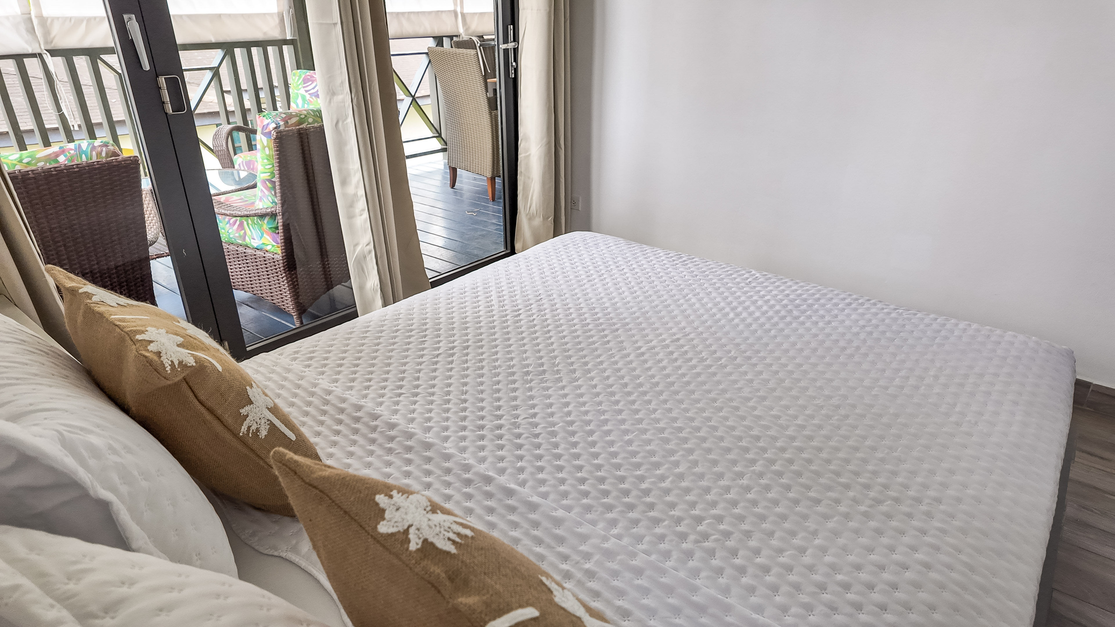 Bright bedroom with plush bed and private balcony seating