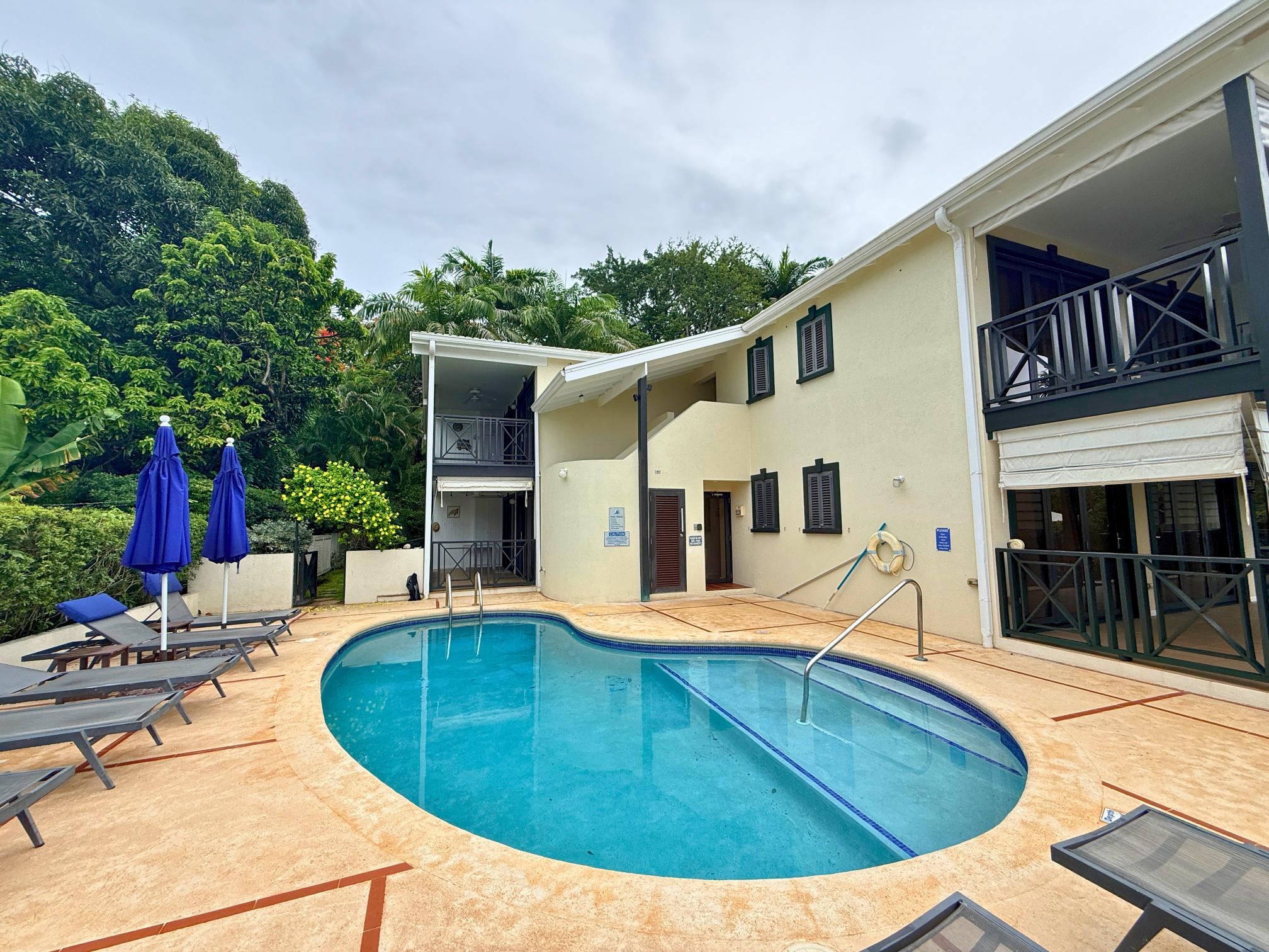 Resort-style pool courtyard with loungers, balconies, and tropical charm