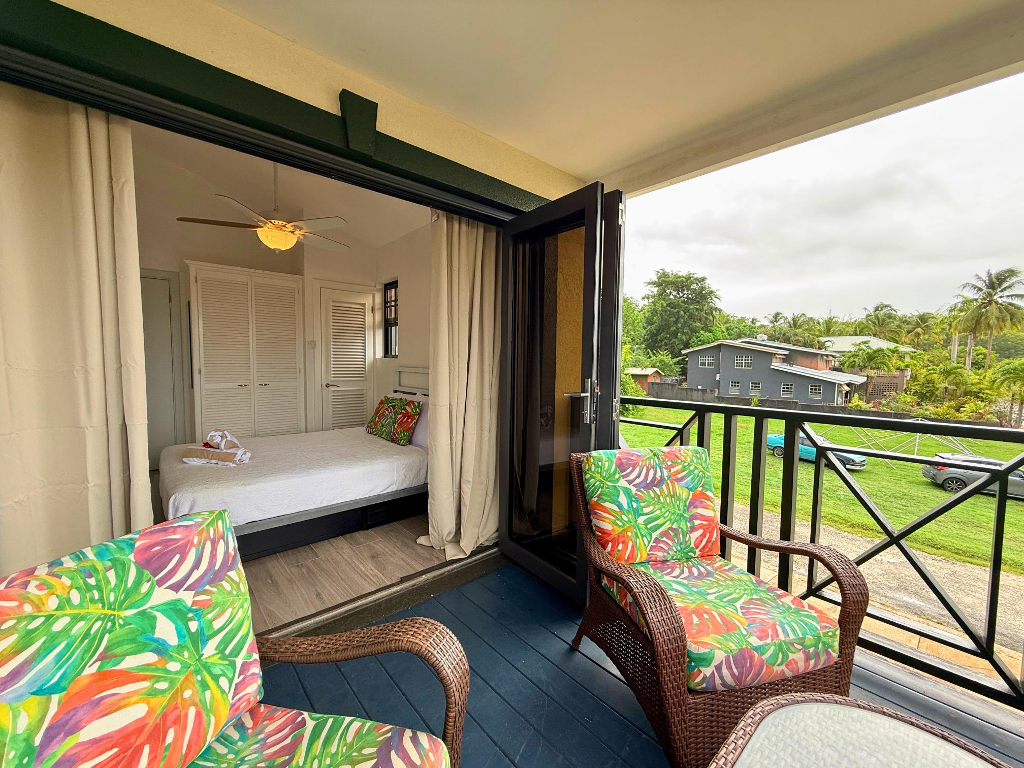 Private tropical balcony with colorful seating and airy bedroom views