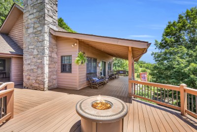 Unwind on this spacious covered deck, complete with a crackling fire pit, classic rocking chairs, and scenic wooded views — the perfect spot to relax morning, noon, or night.