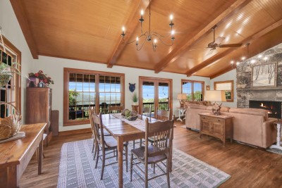 Unwind in this warm wood-beamed great room, featuring a cozy fireplace, inviting dining space, and scenic deck views — the perfect gathering spot for mountain memories.