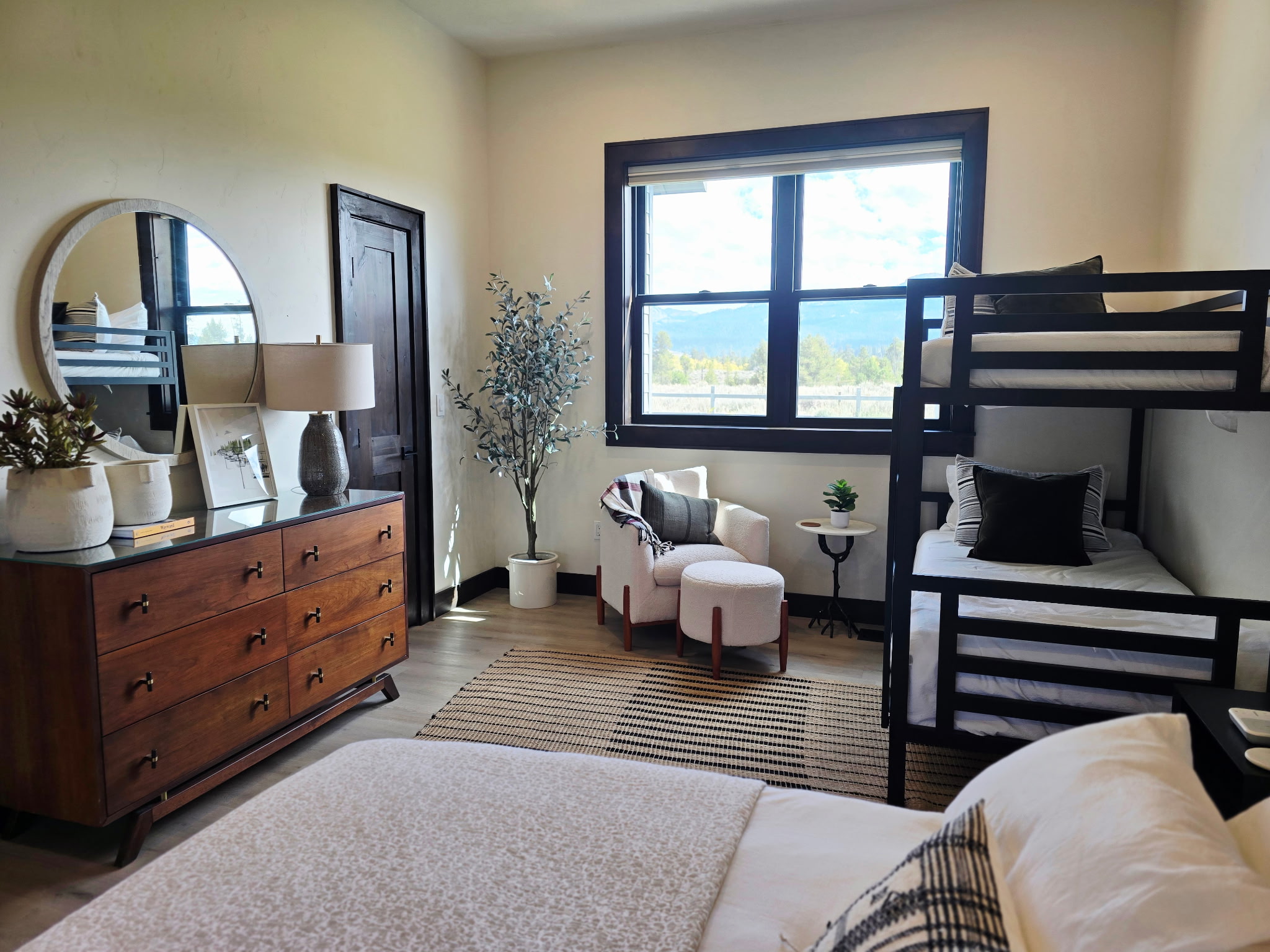 Bright family-friendly bedroom with bunks, cozy chair, and scenic window views