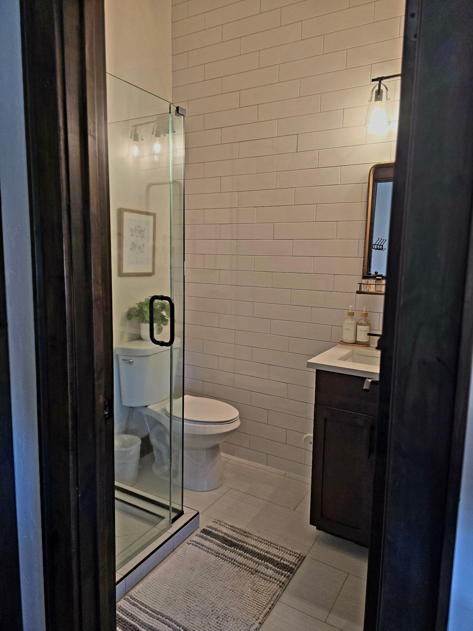 Modern bathroom with glass shower, subway tile, and warm lighting