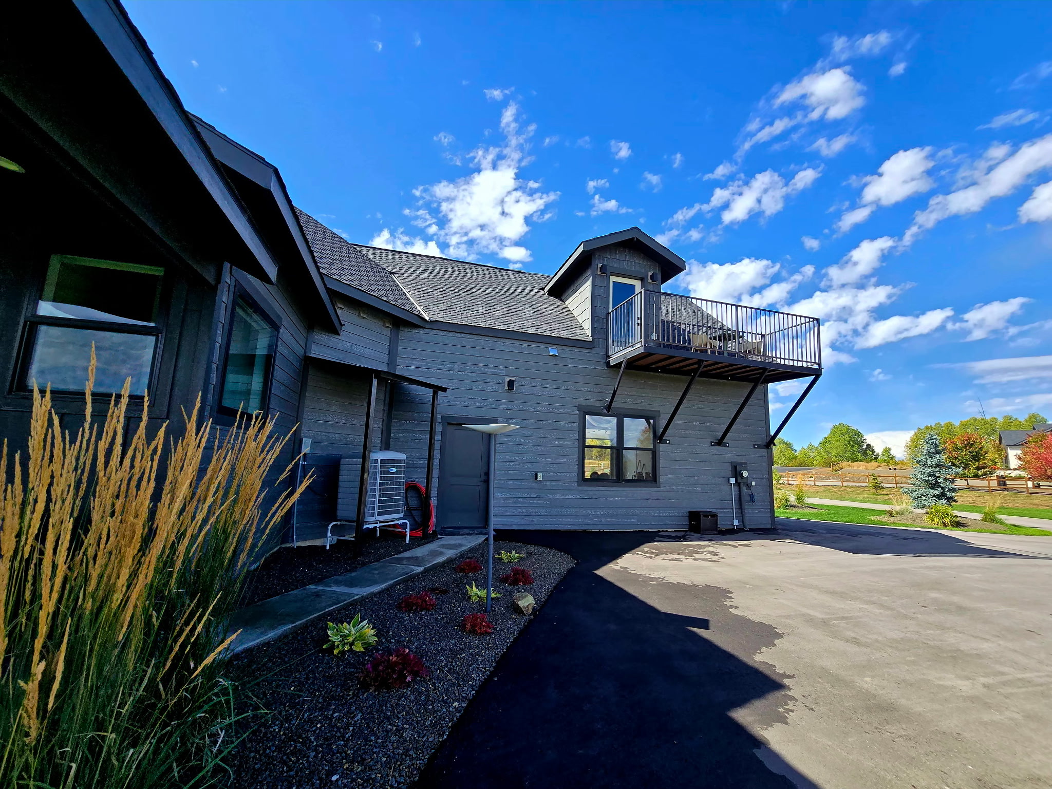 Modern exterior with private balcony, spacious drive, and fresh landscaping