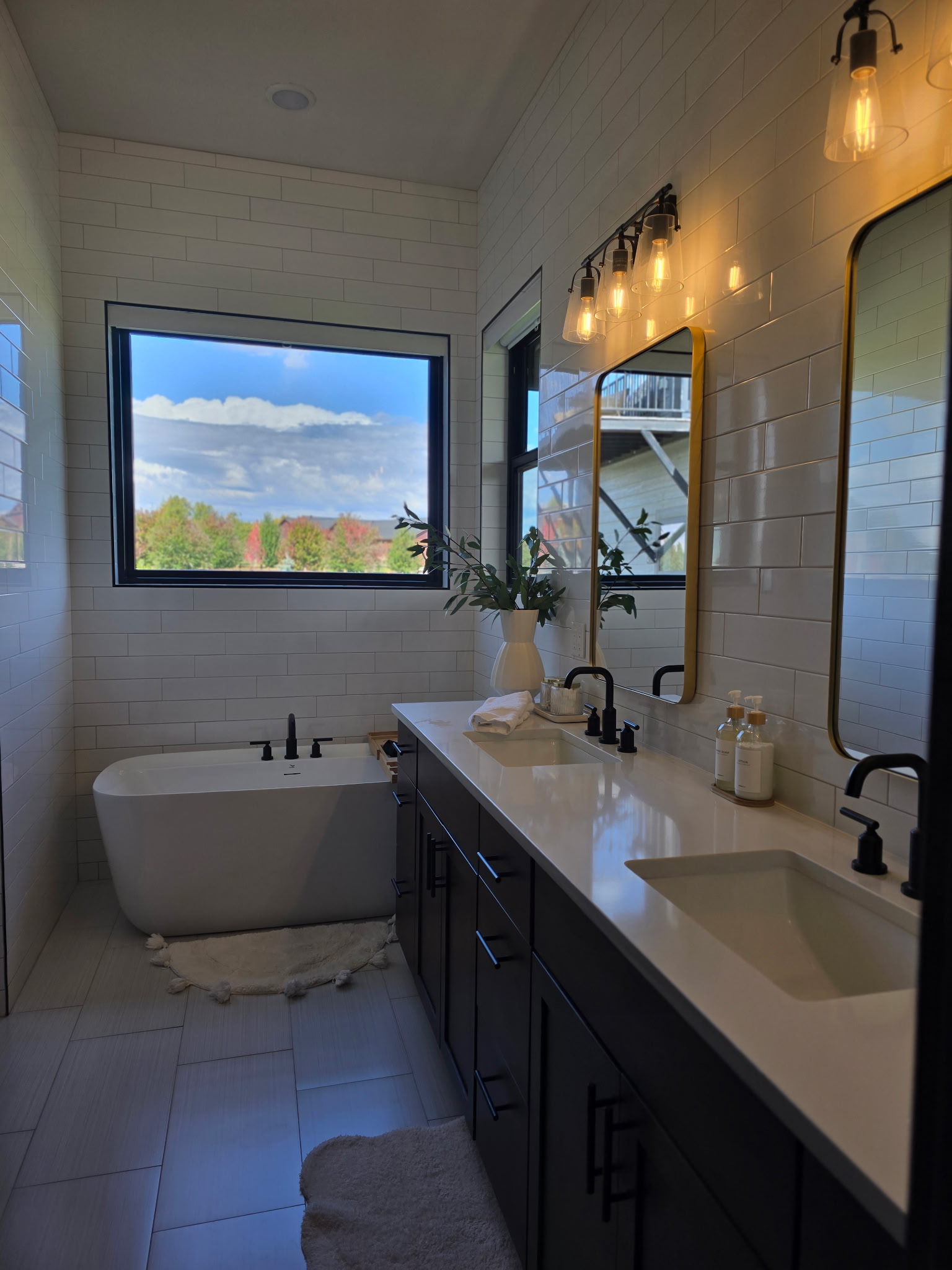 Spa-like bathroom with double vanity, soaking tub, and scenic window views