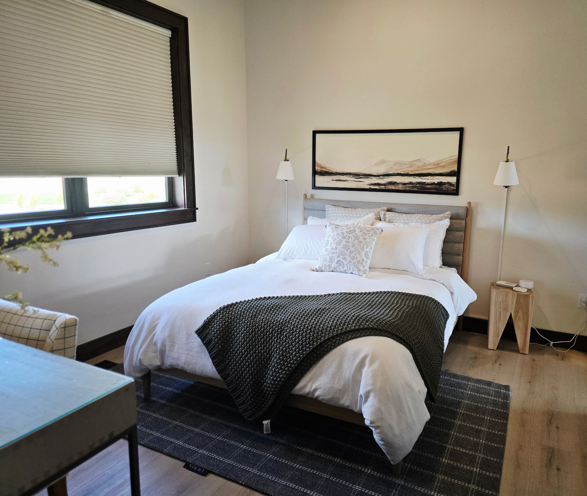 Bright modern bedroom with plush linens, warm wood accents, and natural light