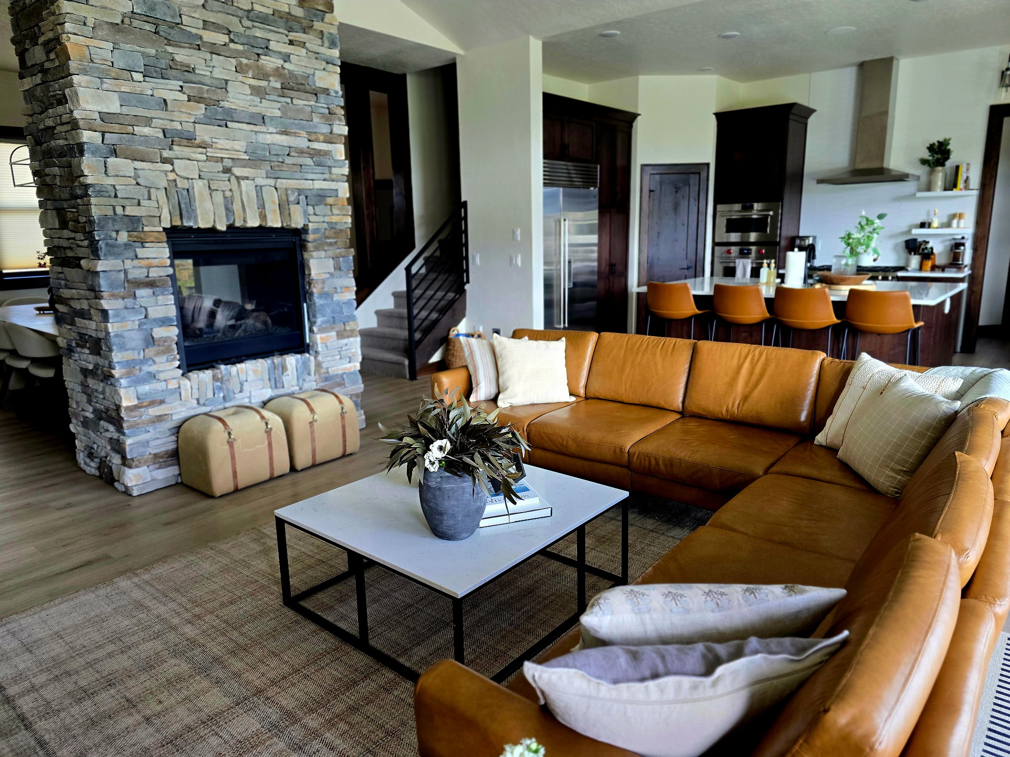 Spacious modern great room with stone fireplace and chef’s kitchen