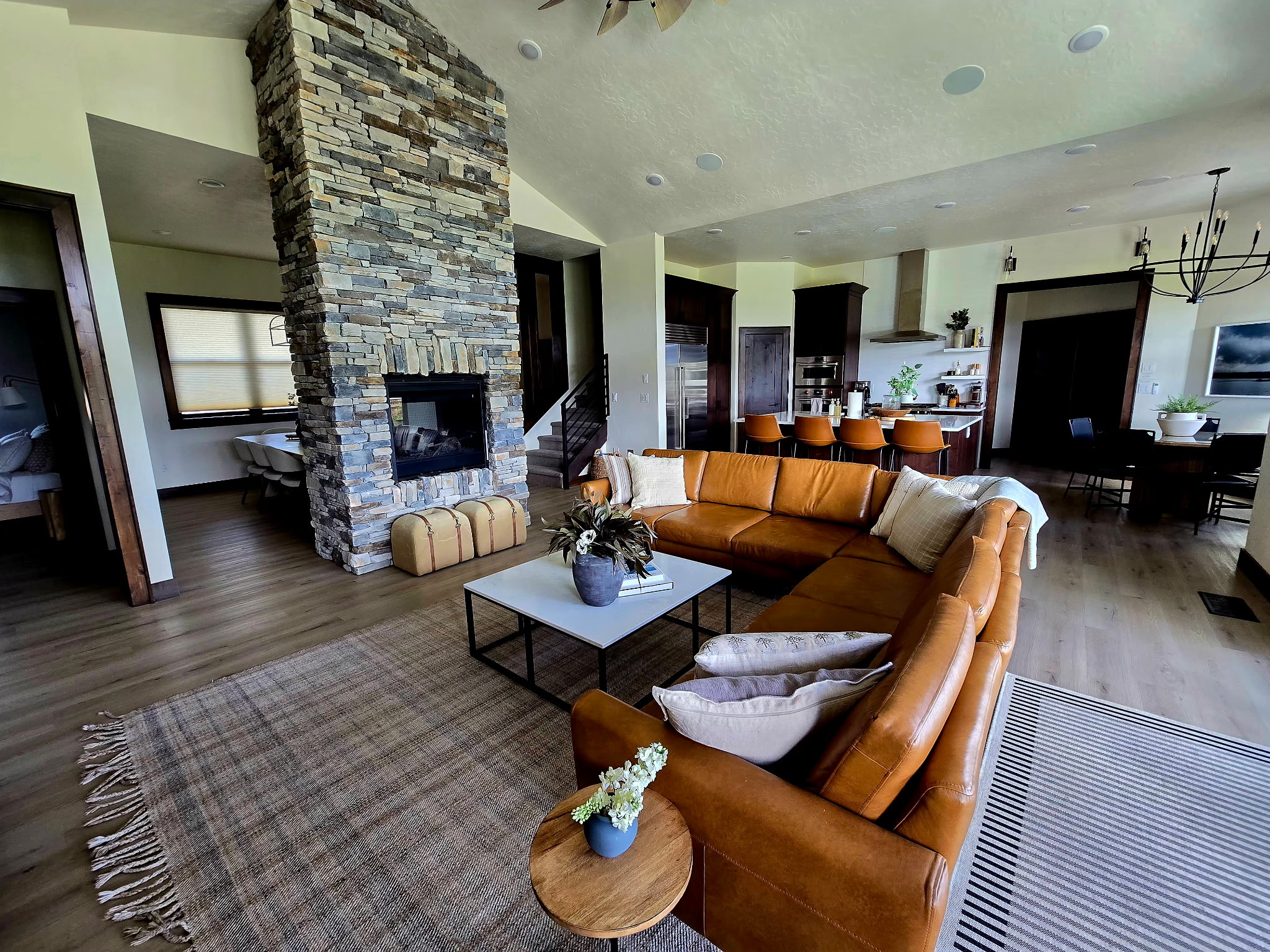 Spacious great room with stone fireplace, leather sectional, and open kitchen