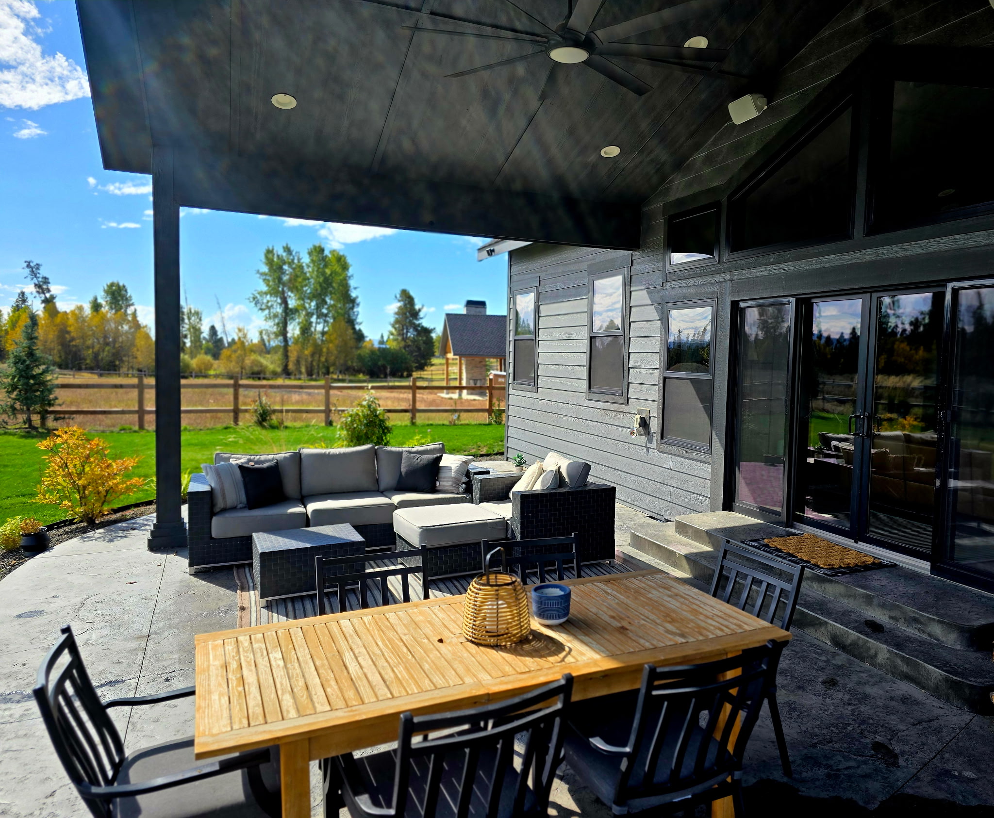 Covered patio with lounge seating, dining table, and peaceful backyard views