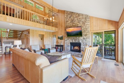 Soaring ceilings, a stunning stone fireplace, open loft views, and direct sightlines to the deck make the vaulted great room at Beech Mountain High one of the most breathtaking spaces in the High Country.