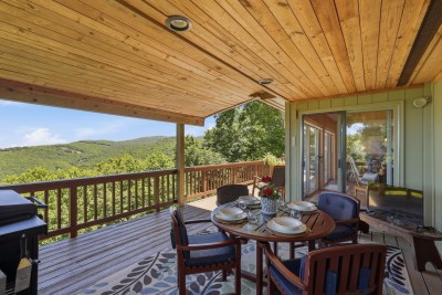 The covered deck is outdoor living at its finest — fire up the grill, gather around the dining table, settle into the seating, and take in stunning mountain views that make every meal an event.