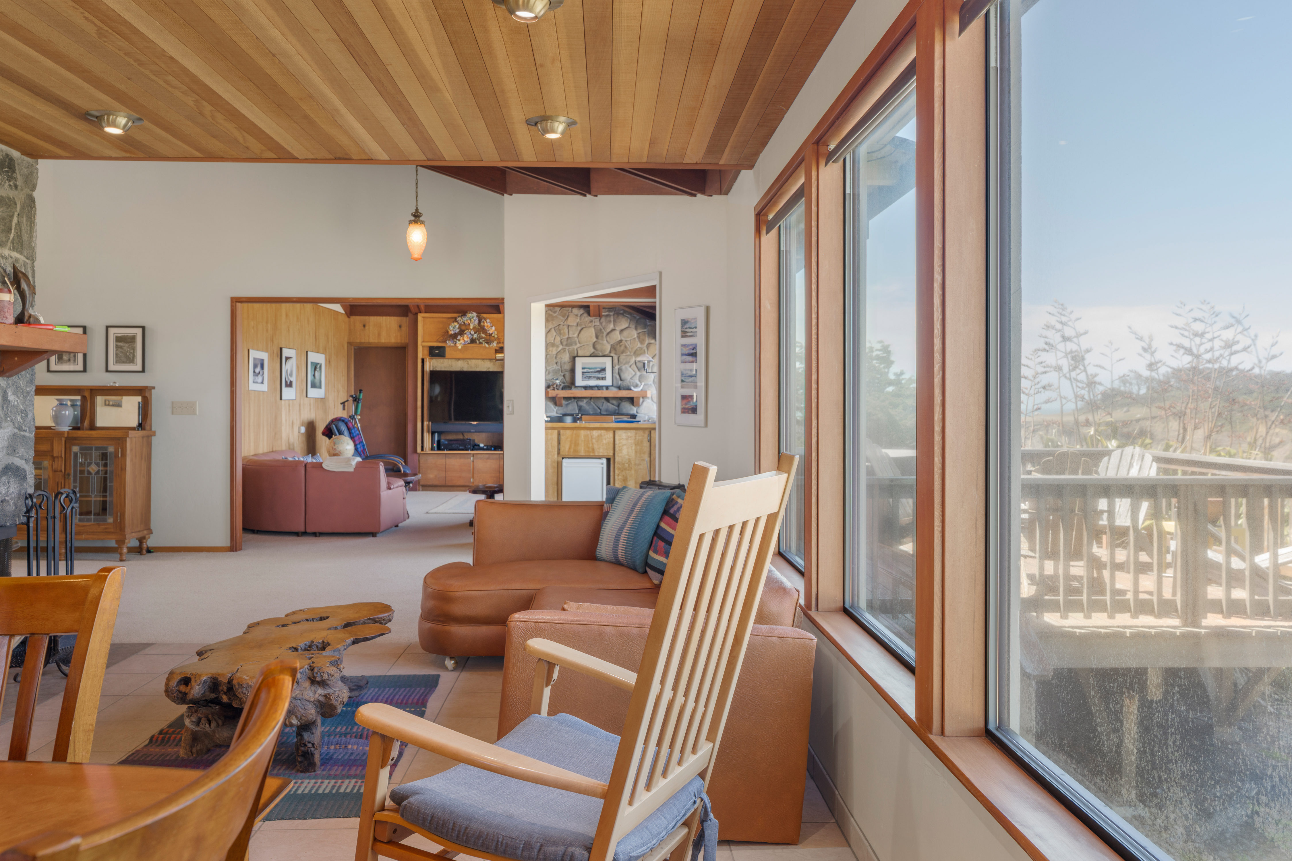 Sunny living space with wood ceilings, big windows, and peaceful views