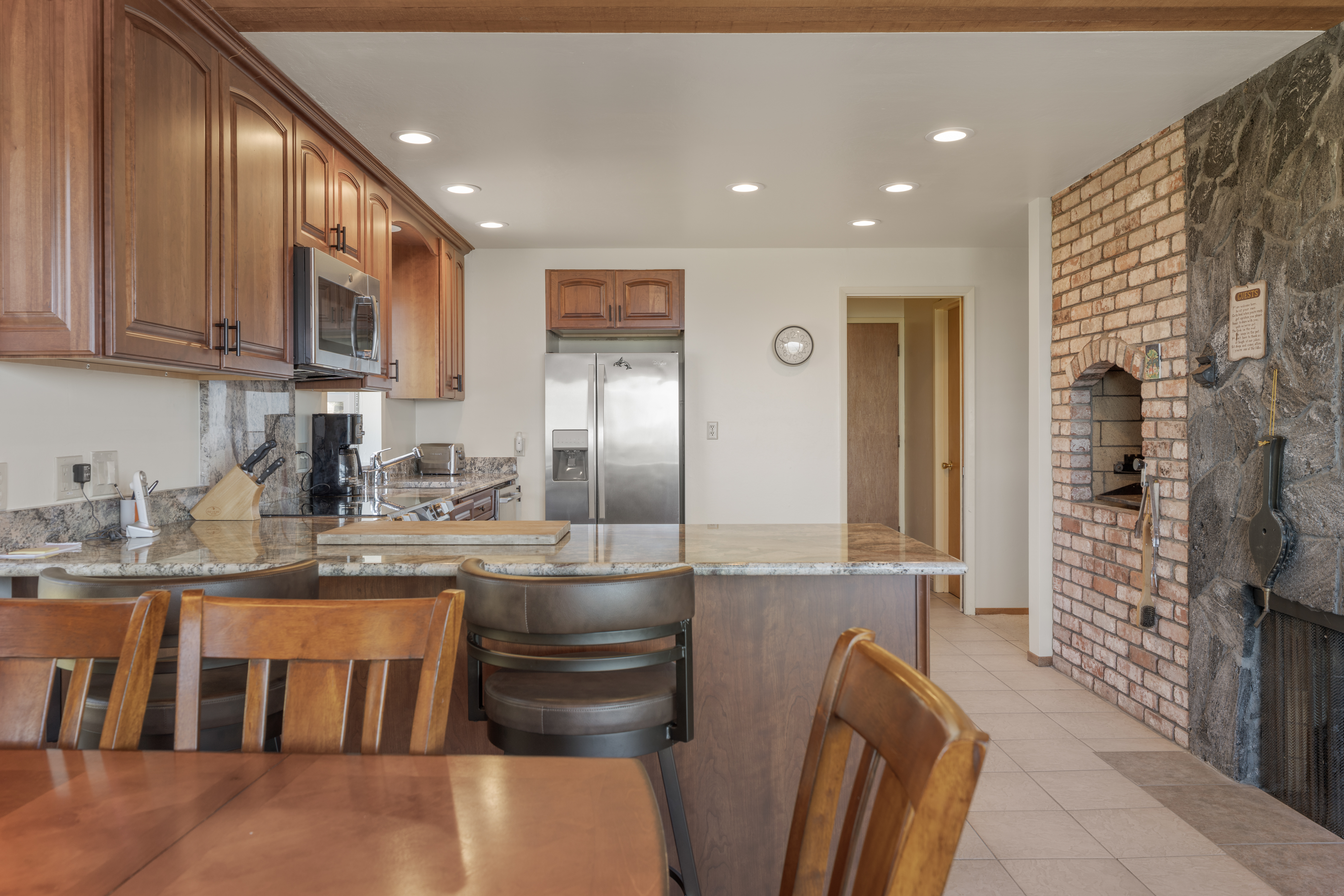 Spacious kitchen with granite bar seating and rustic fireplace charm
