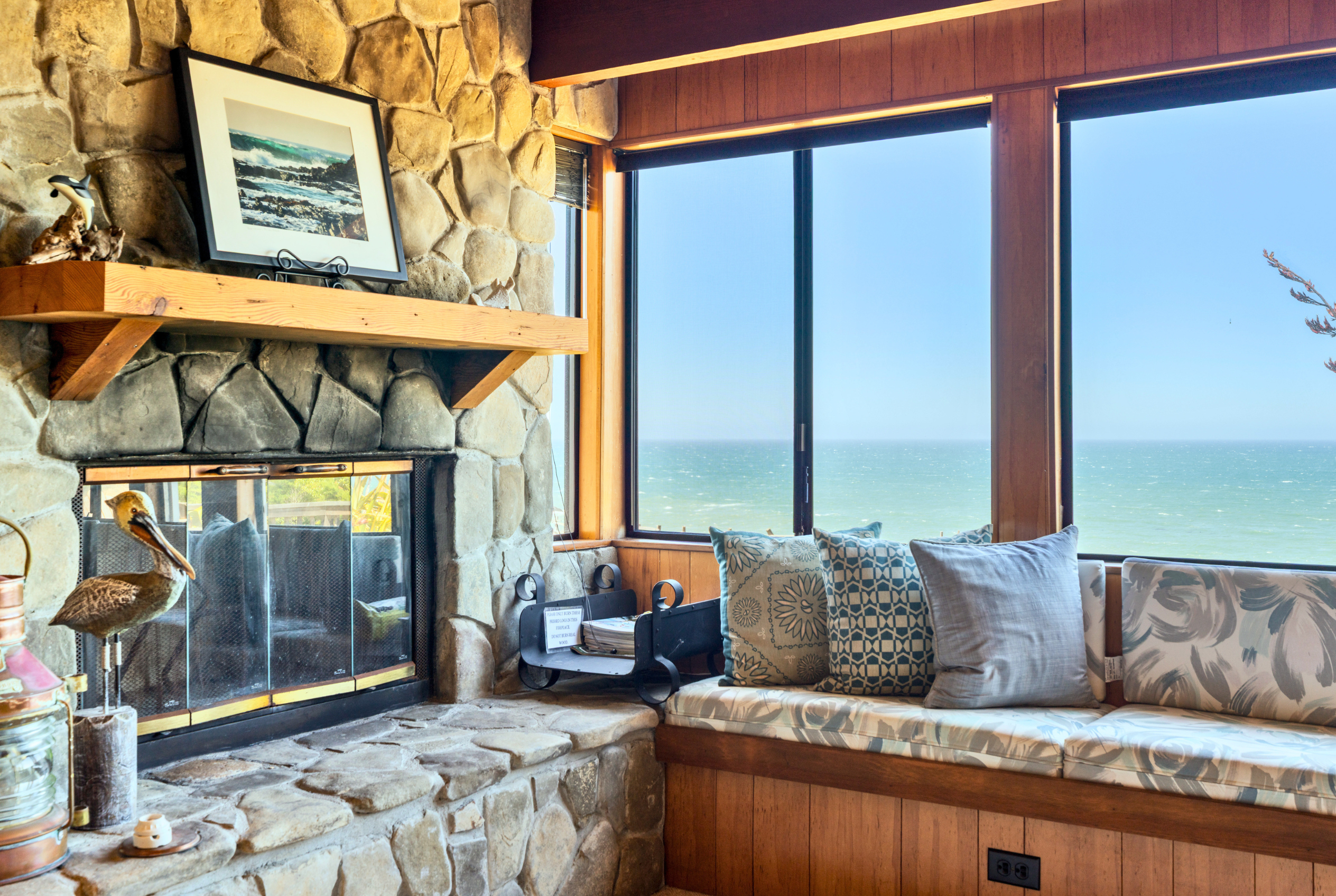 Cozy stone fireplace nook with window seat and stunning ocean views