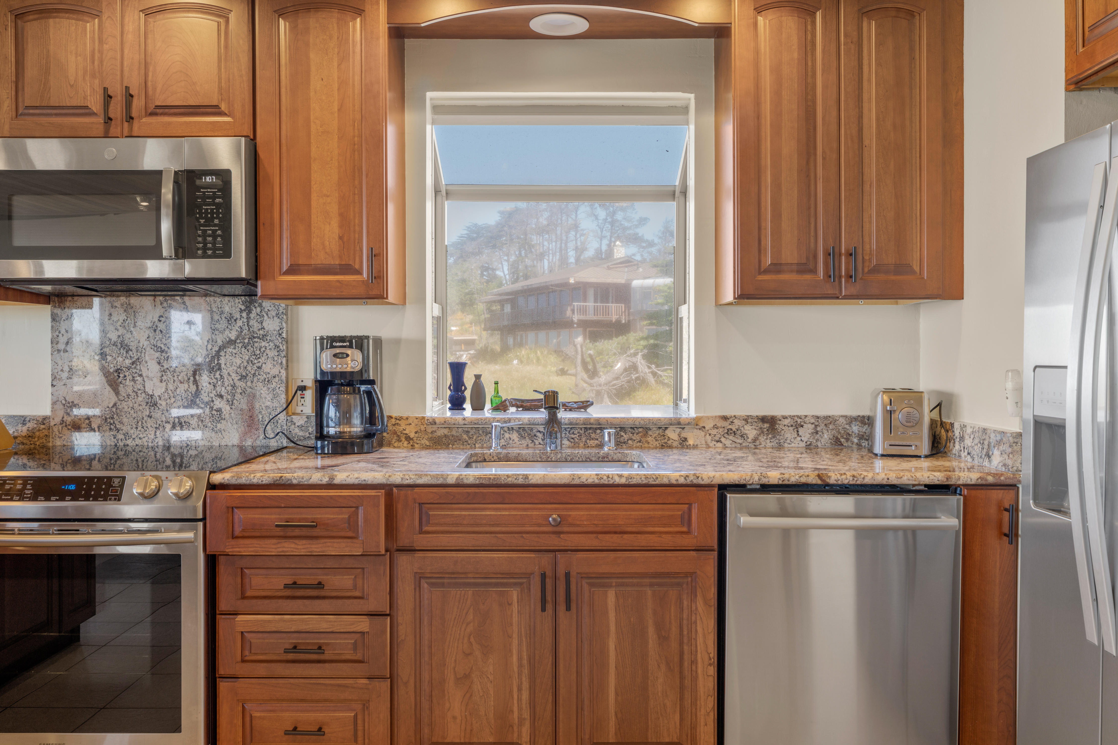 Bright kitchen with granite counters, stainless appliances, and scenic view