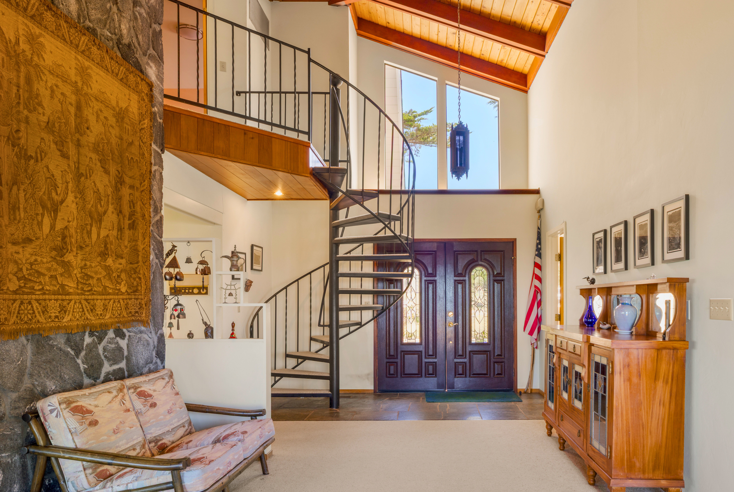 Bright grand entry with spiral staircase and vaulted wood ceilings