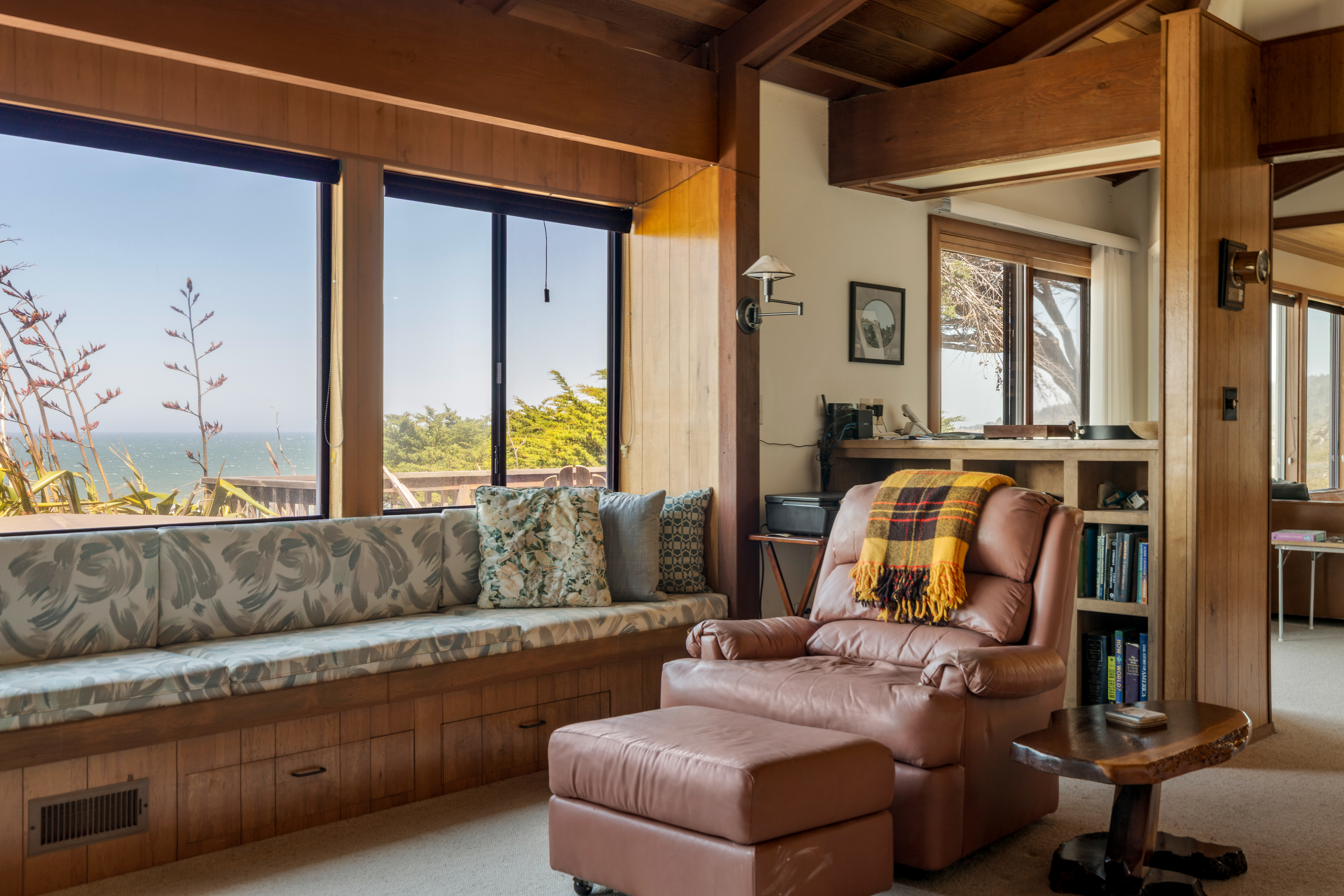 Cozy ocean-view reading nook with window seat and leather lounge chair