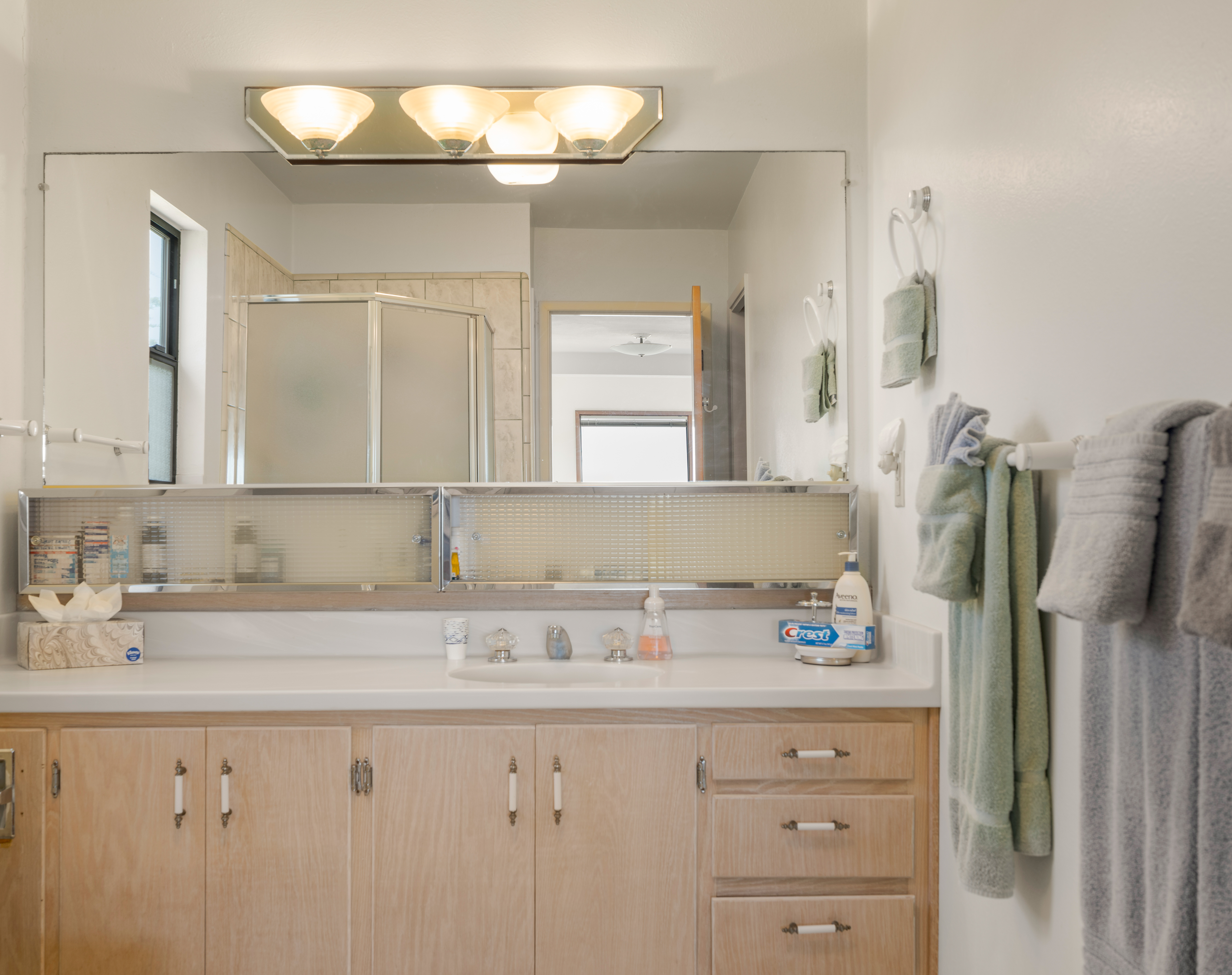 Bright bathroom with large vanity, mirror, and plenty of storage