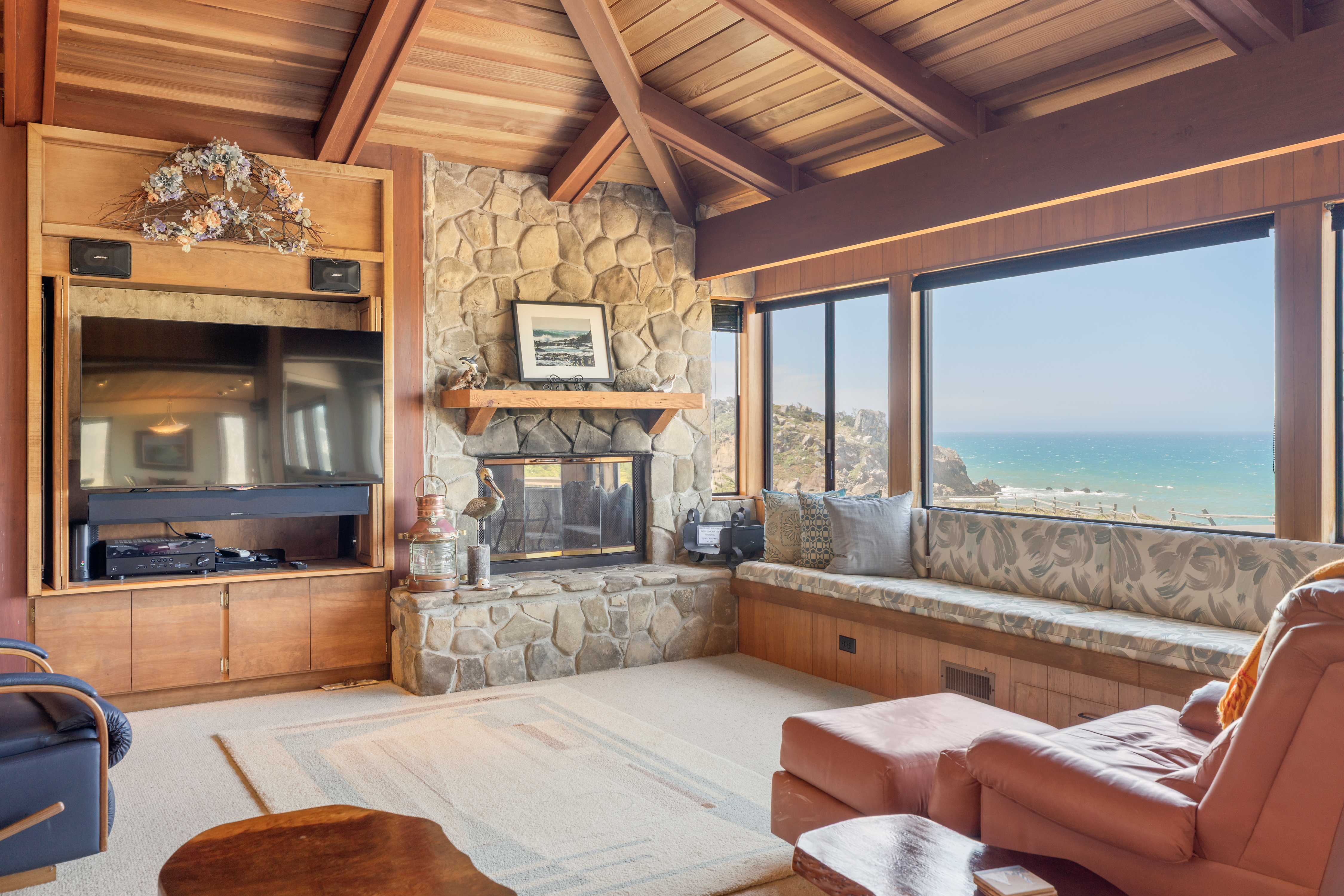 Cozy wood-beamed living room with fireplace and sweeping ocean views