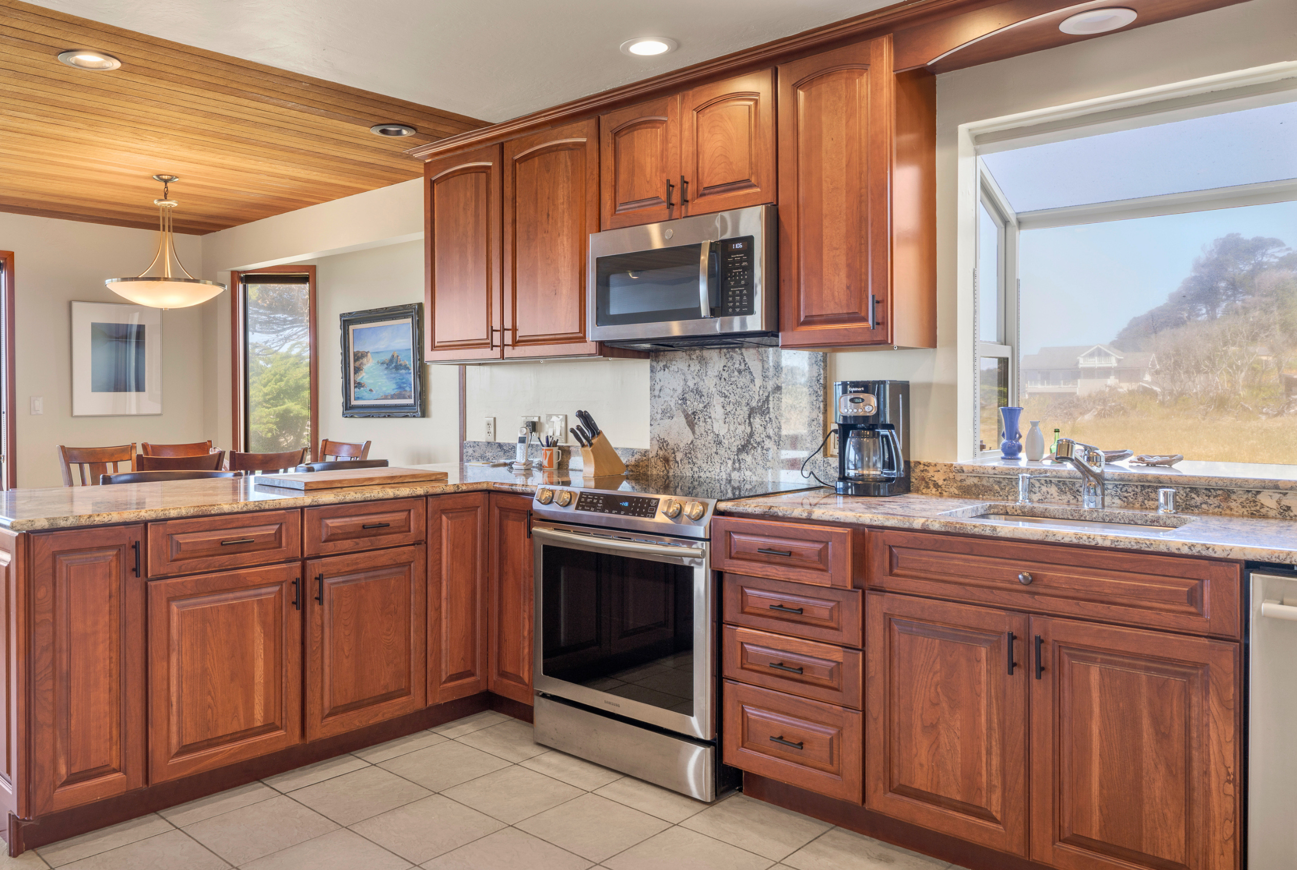 Bright gourmet kitchen with granite counters, stainless appliances, and views