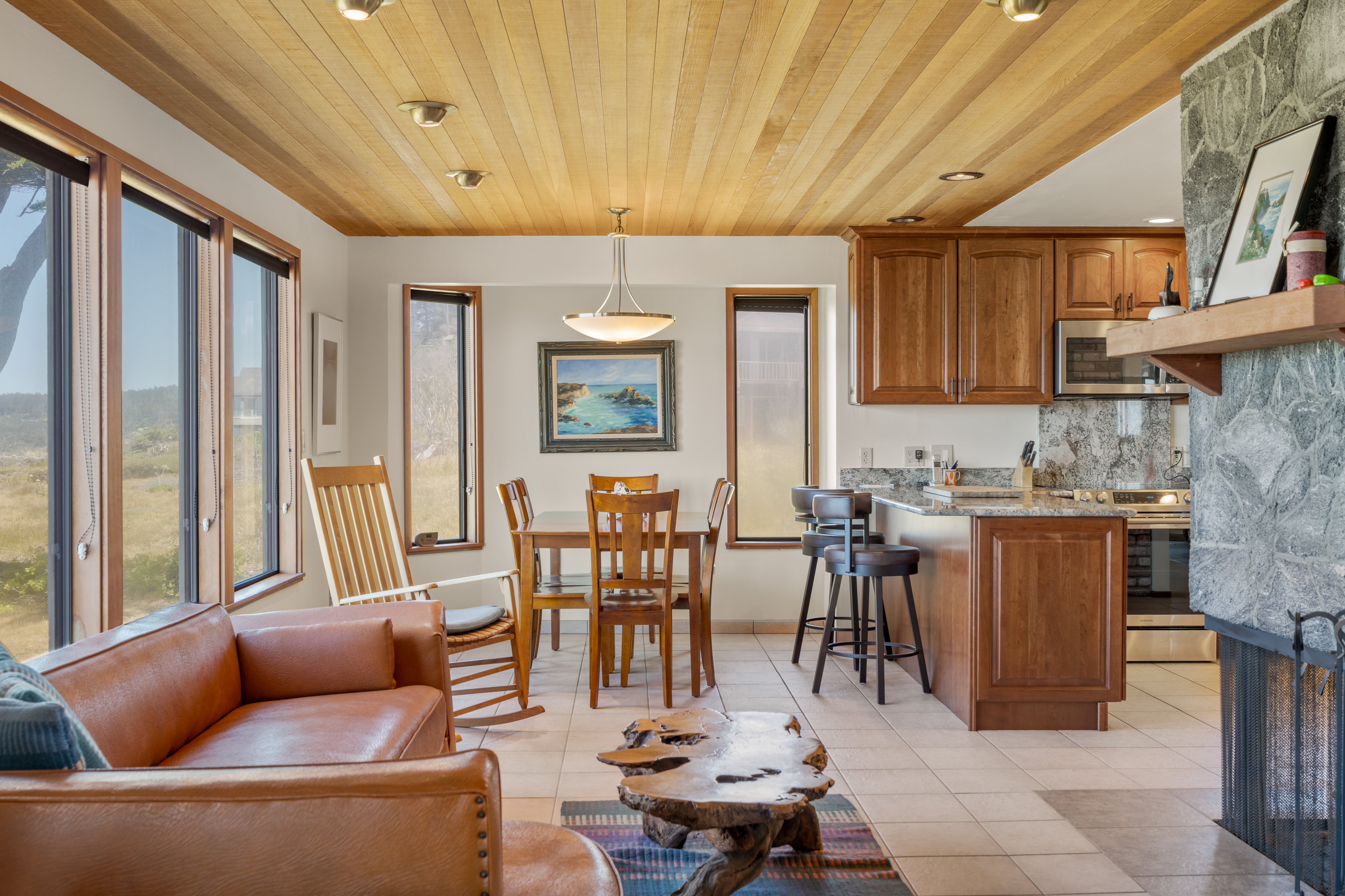 Bright open living space with big windows, fireplace, and full kitchen
