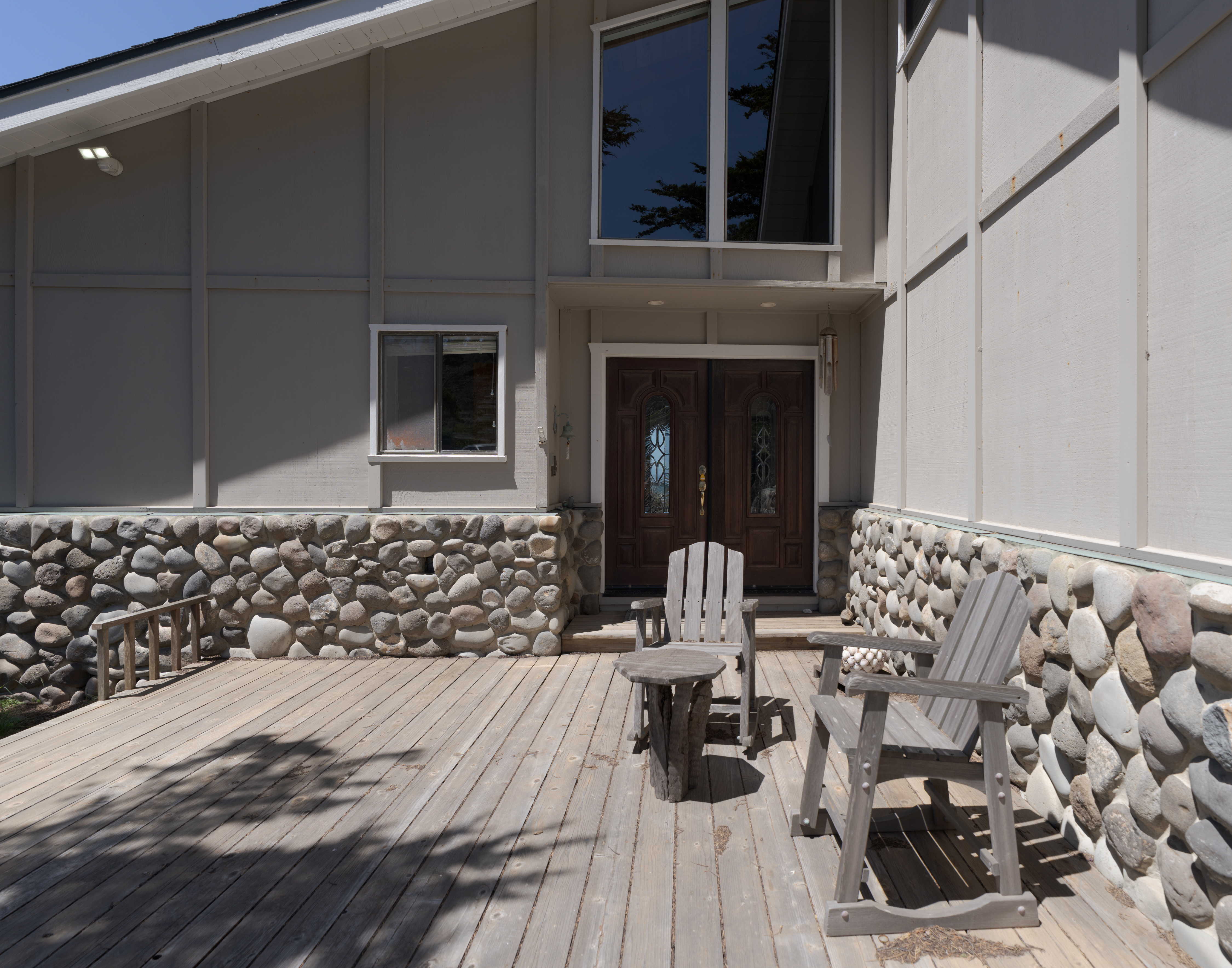 Welcoming front deck with seating, stone accents, and grand entry