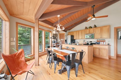 The sunny open kitchen and dining space at Beech Mountain Place is bright and inviting — soaring vaulted wood ceilings and abundant natural light create a warm atmosphere perfect for cooking and gathering together.