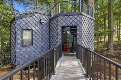 Discover this architectural forest retreat, featuring a striking elevated entry and a rooftop deck that puts the surrounding mountain views on full display.