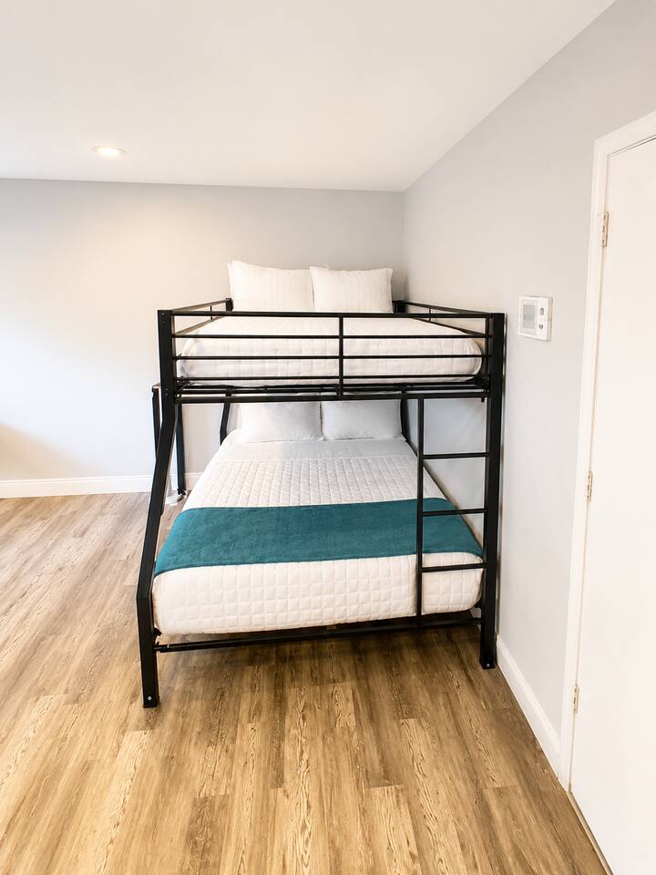 Relax and unwind in a comfortable queen-over-full bunk bed with soft linens and cozy bedding, providing a restful night's sleep for two to three guests.