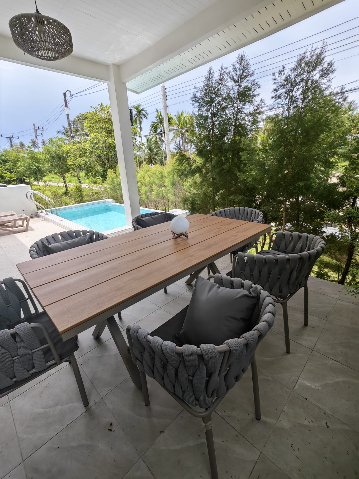 Covered poolside patio with outdoor dining and lush tropical views