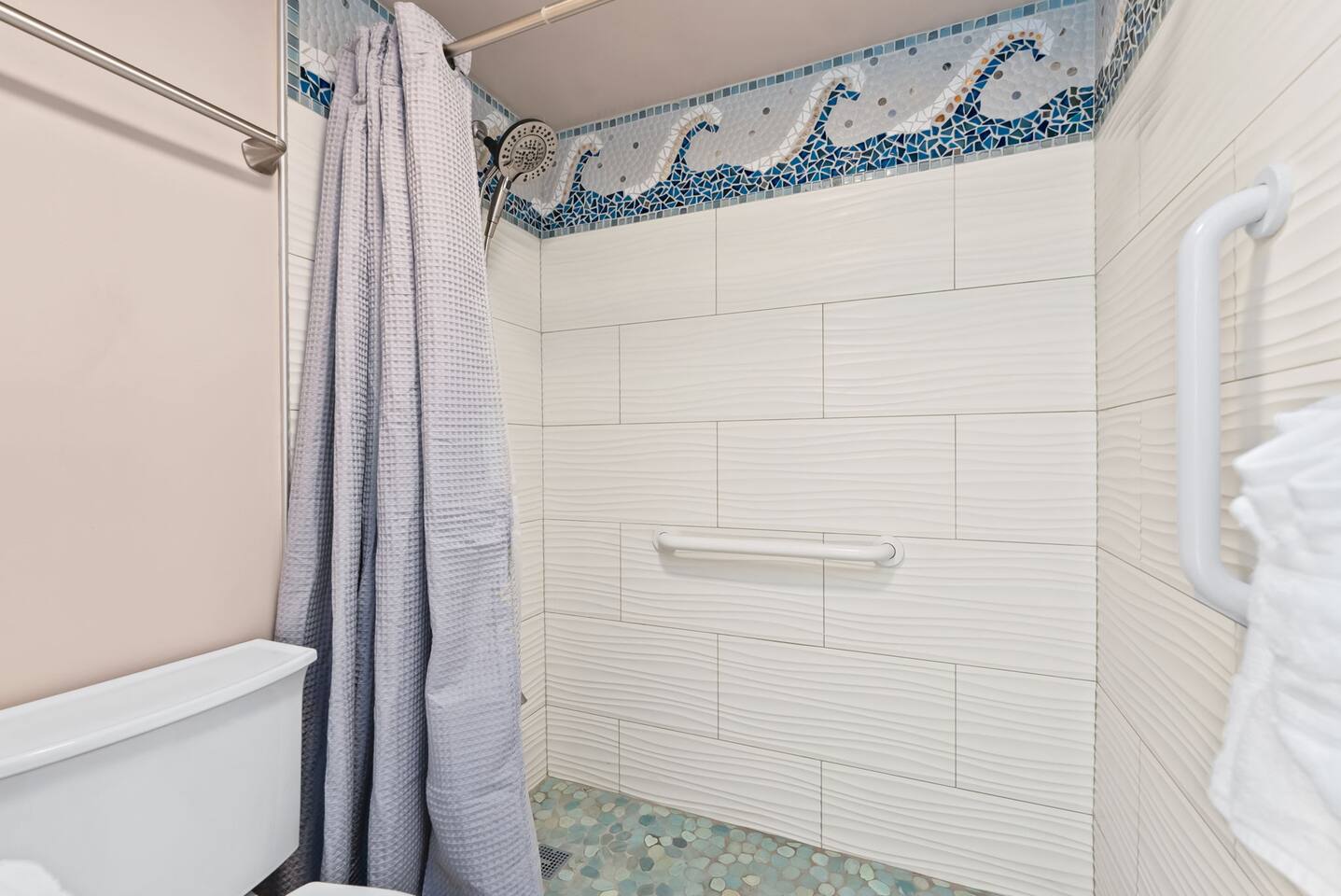 Step into the updated stand-up shower with a large rain showerhead for a refreshing experience after a day in the sun.