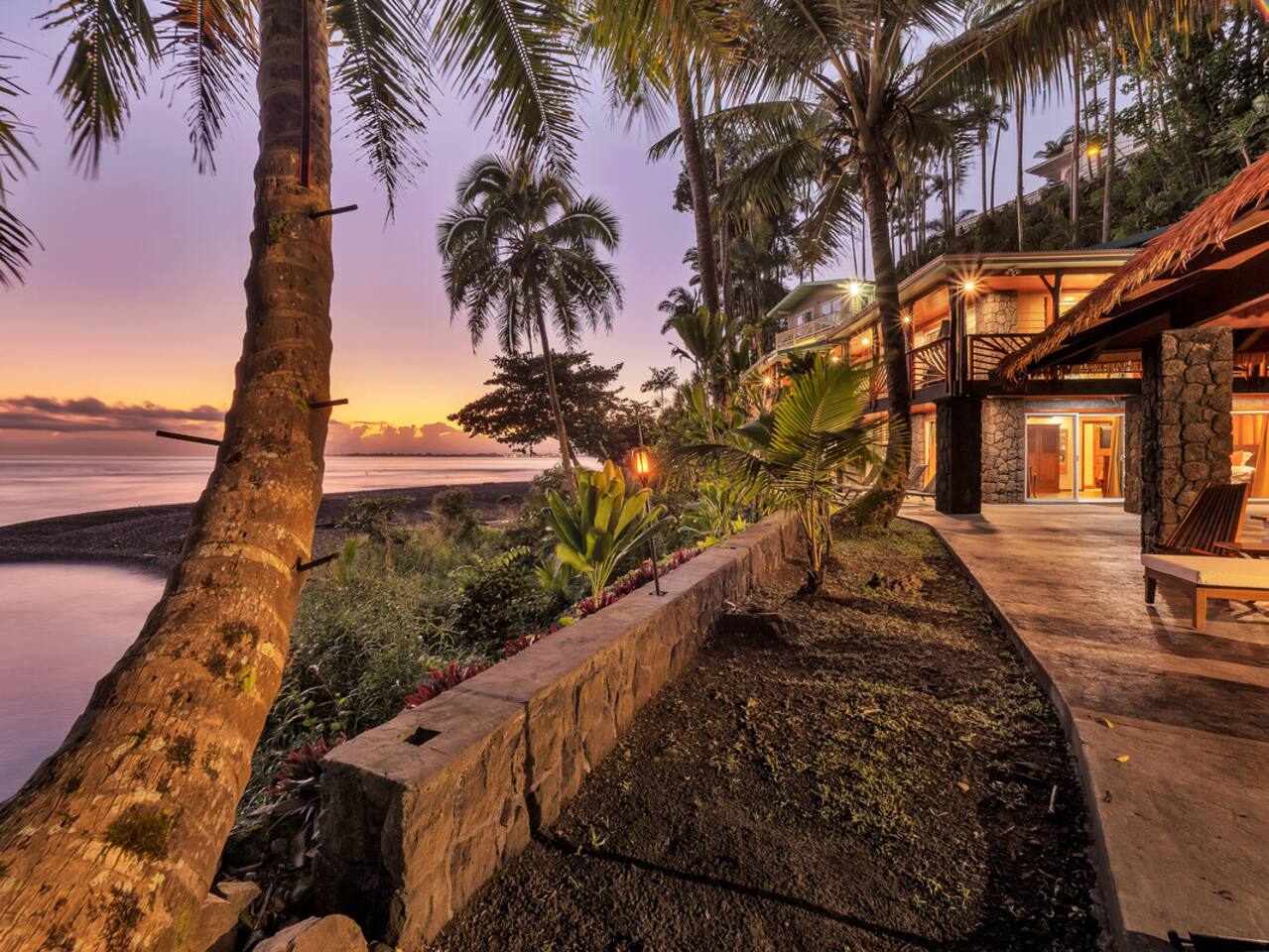 The breathtaking beauty of the Honoli'i Hale is framed by the lush green mountains and the serene Pacific Ocean.