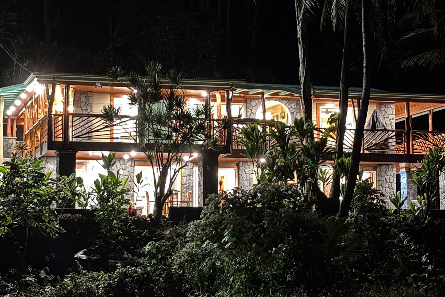 Nighttime brings a special kind of magic to this home, with the glowing lights from the lanai casting a warm, inviting ambiance against the backdrop of the dark ocean.